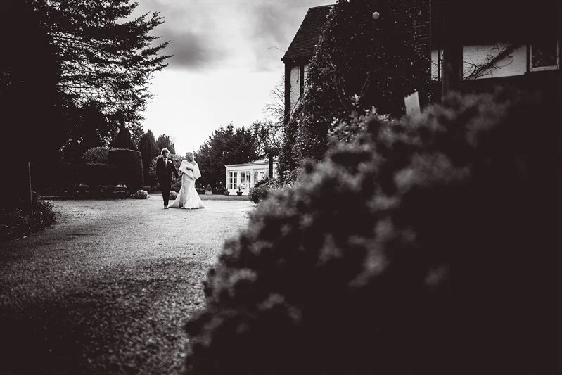 Black & white photo of the bride and groom walking hand in hand during their portrait session outside at Hayne House.