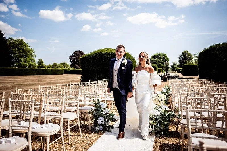Colour photo of the bride and groom walking in Eastwell manor grounds