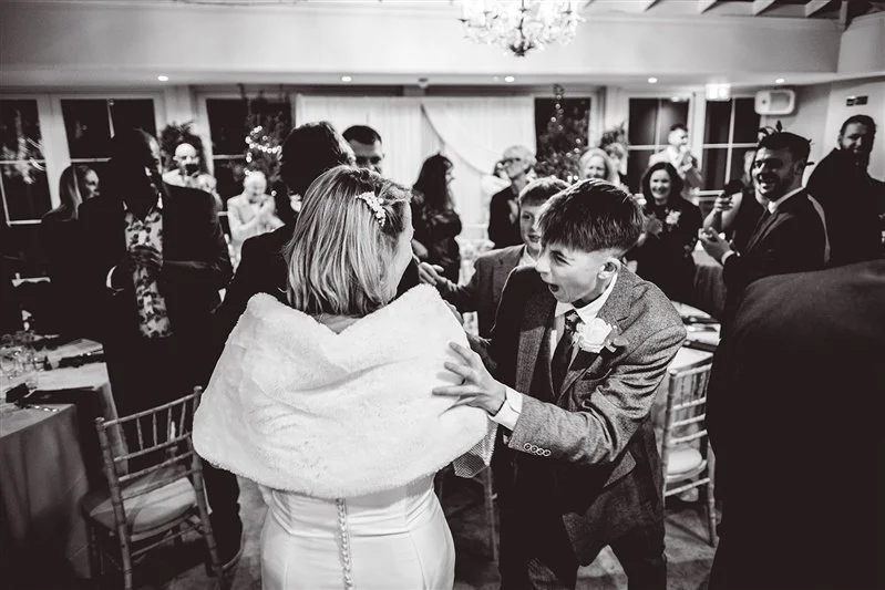 Black & white photo of the couple walking into the wedding breakfast being congratulated on the way