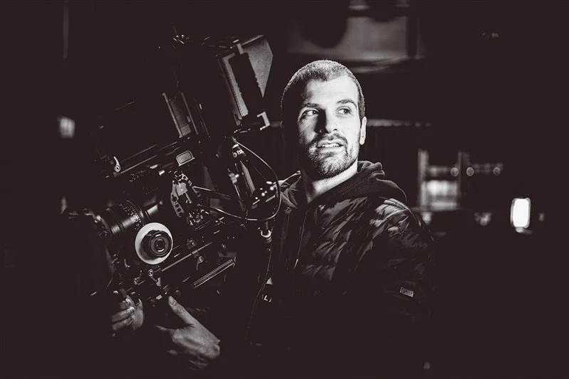 Black and white photo of a film maker holding his video camera during a shoot.