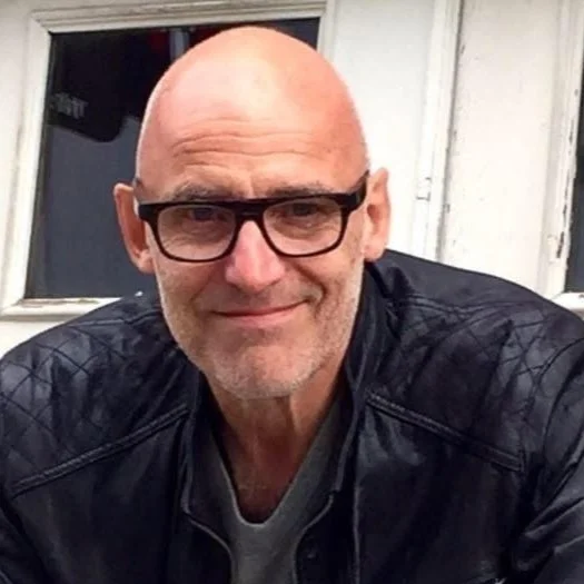 Bald man with glasses and a leather jacket.