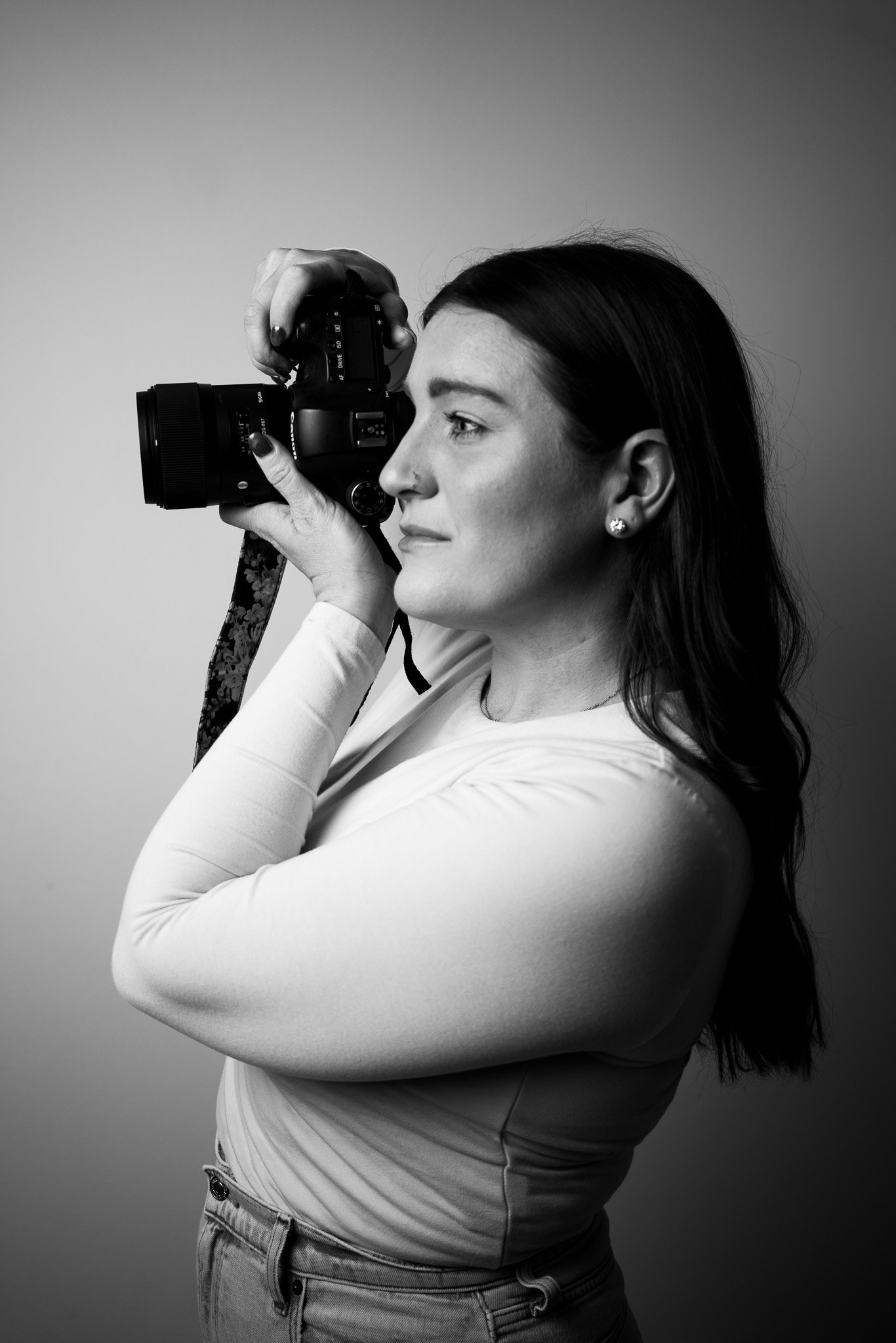 Black and white photo of a woman holding a camera to her eye, profile view