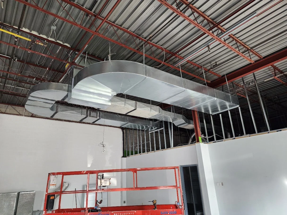 Construction site with new HVAC ductwork installation in progress.