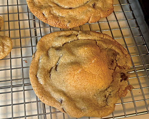Close-up of two chocolate chip cookies cooling on a wire rack.