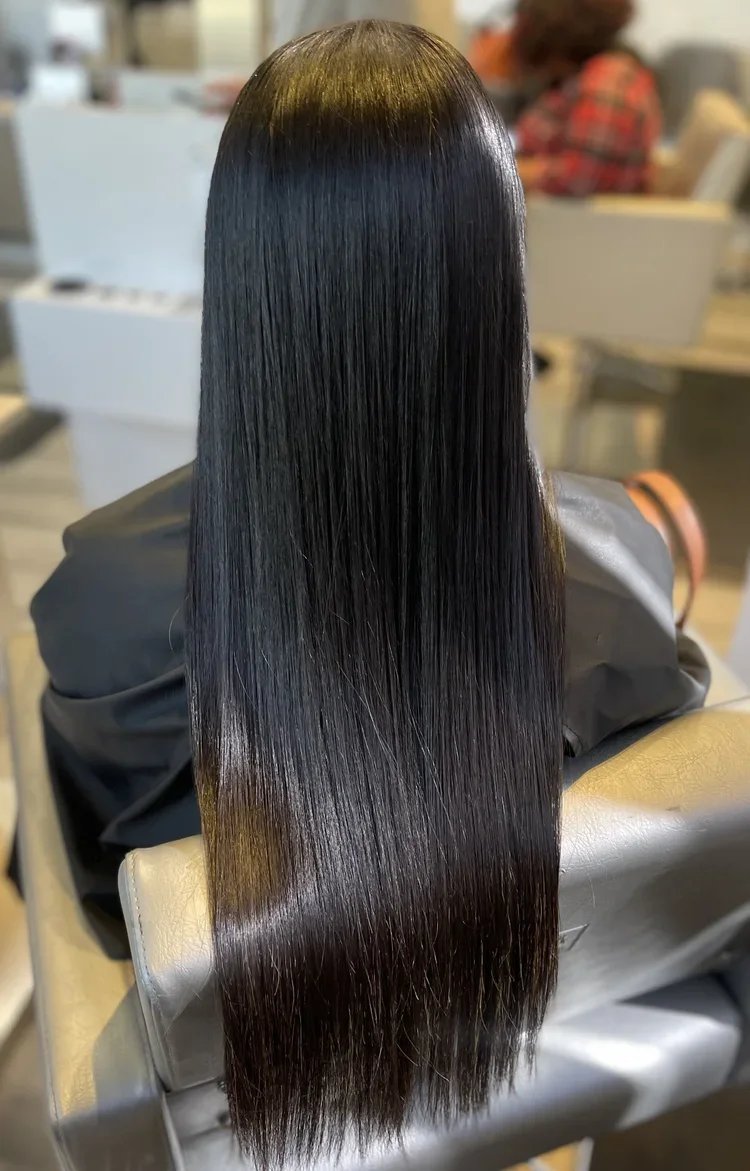 Stylist smoothing a client’s hair during a professional keratin treatment consultation at Versus Salon in Virginia Beach.