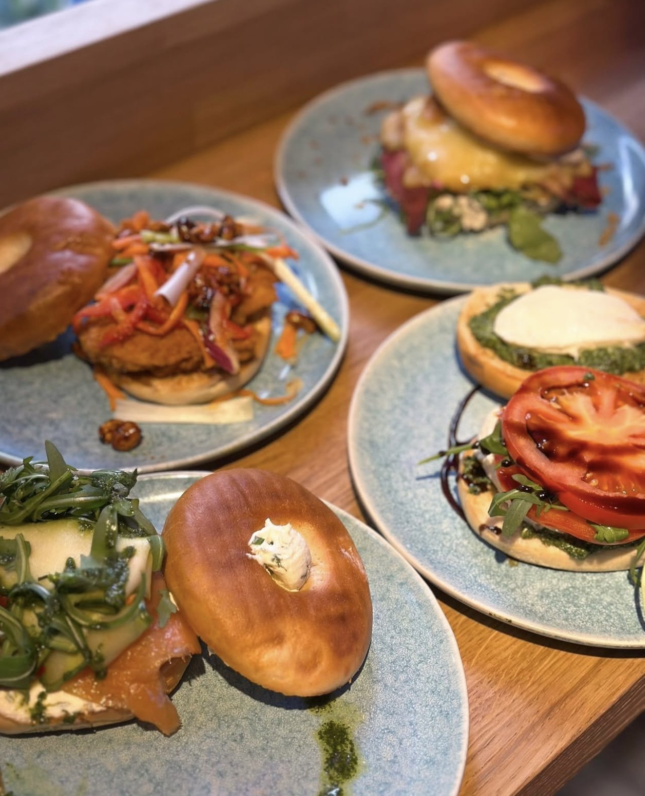 Assorted gourmet open-faced sandwiches with fresh vegetables, cheeses, and various toppings on blue ceramic plates.