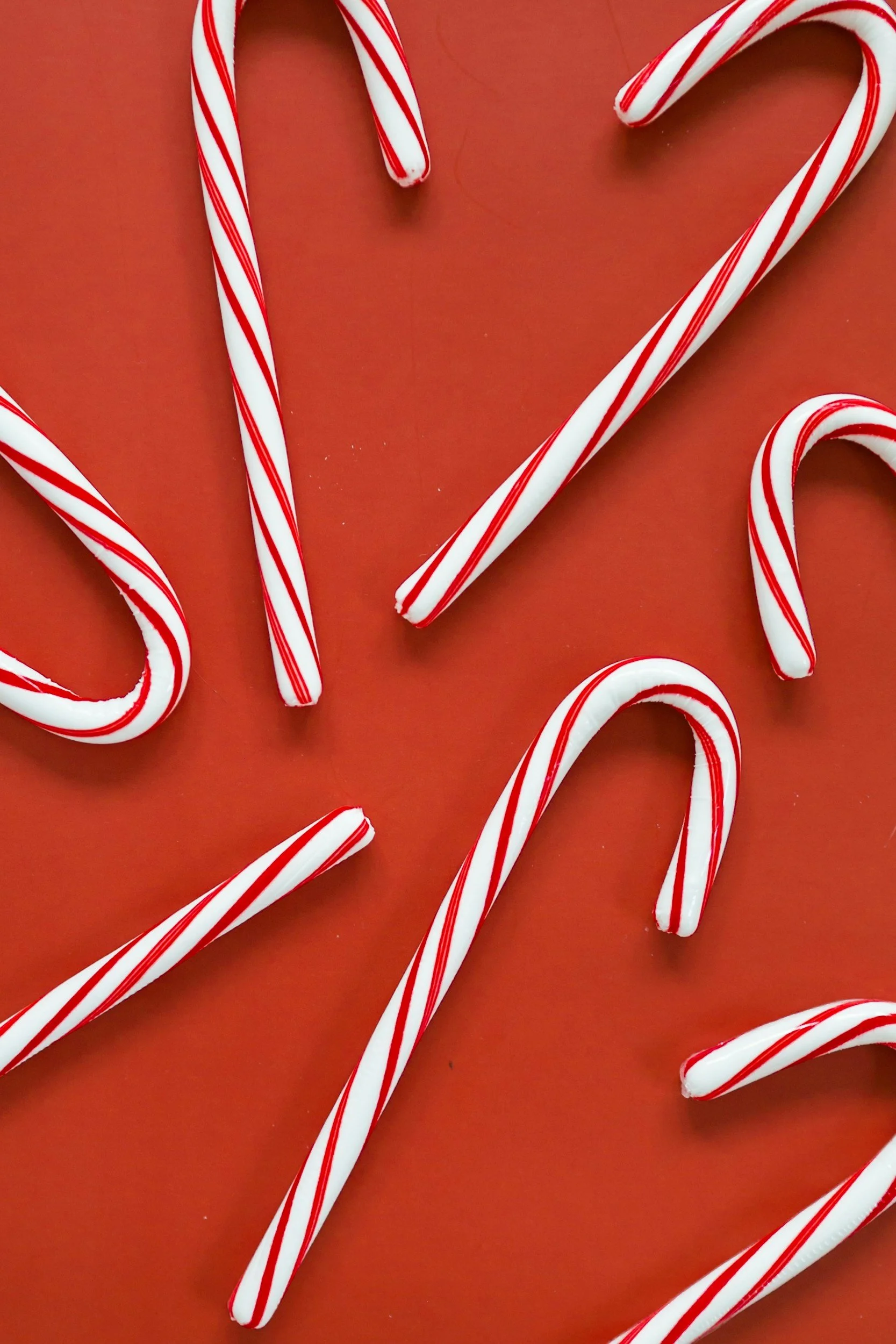 Red and white striped candy canes on a red background.