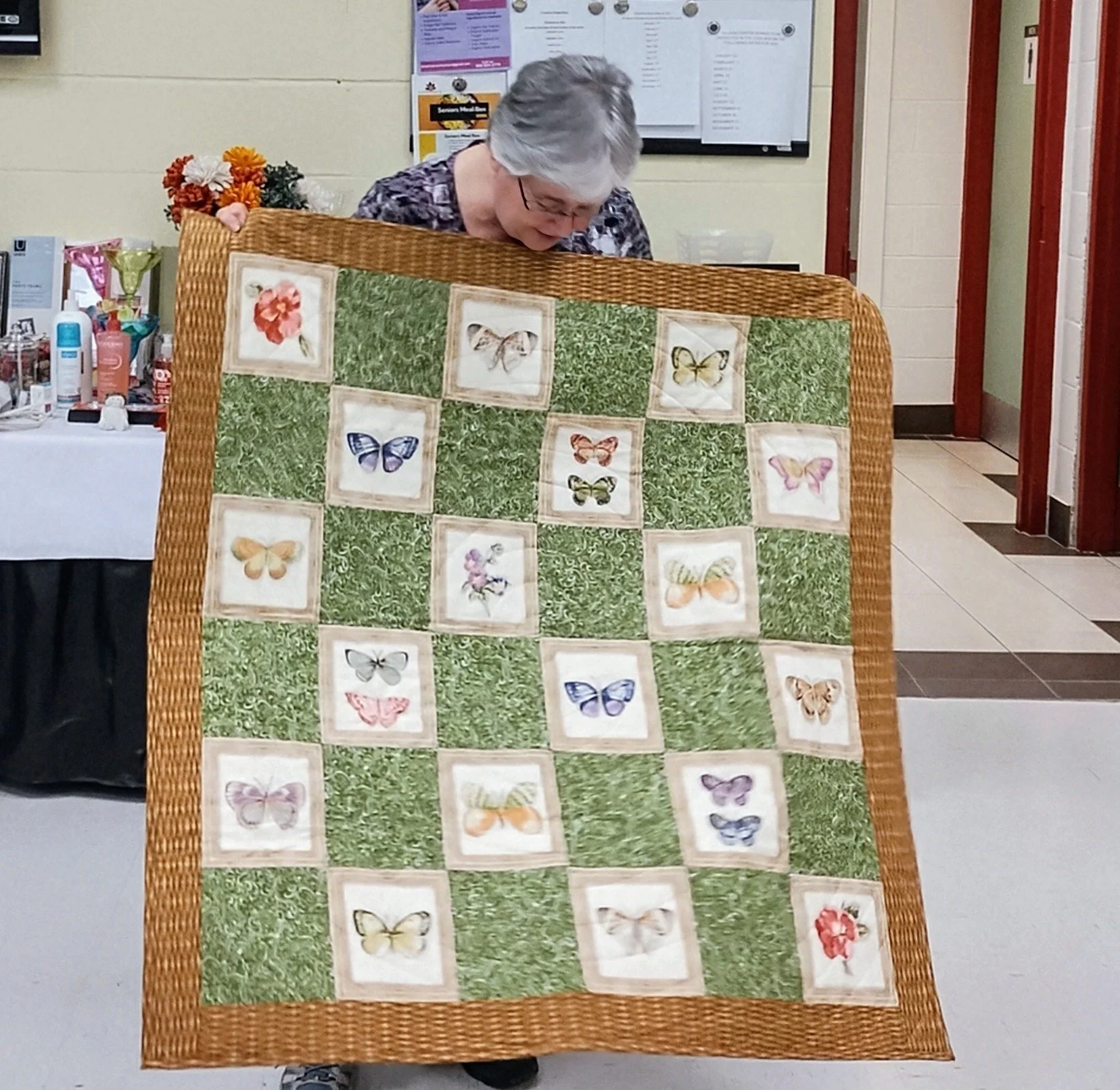 Person holding a quilt with butterfly designs and green panels