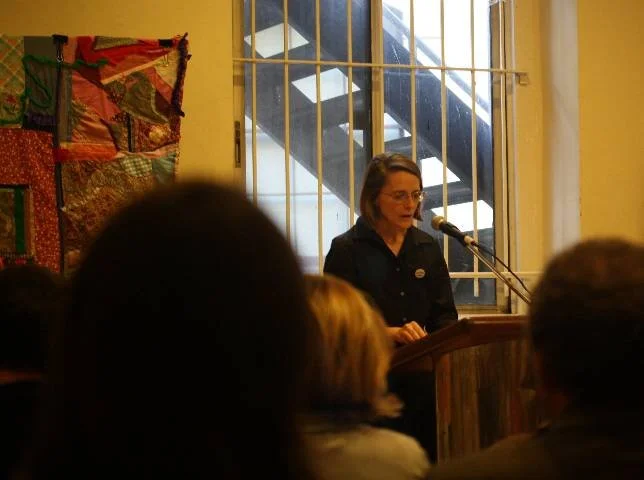 Photo of Marisa Figueriredo speaking at the Shulmaith Firesone memorial
