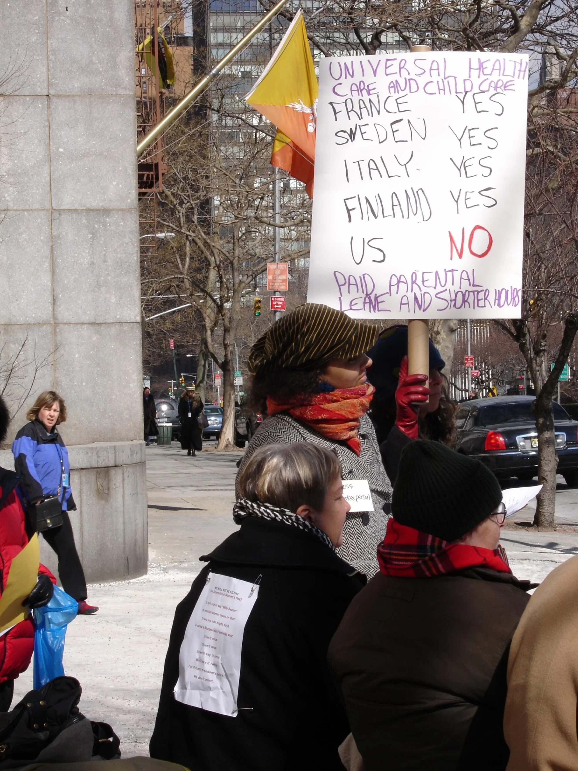 Photo of a woman holding a protest sign comparing which countries have universal healthcare