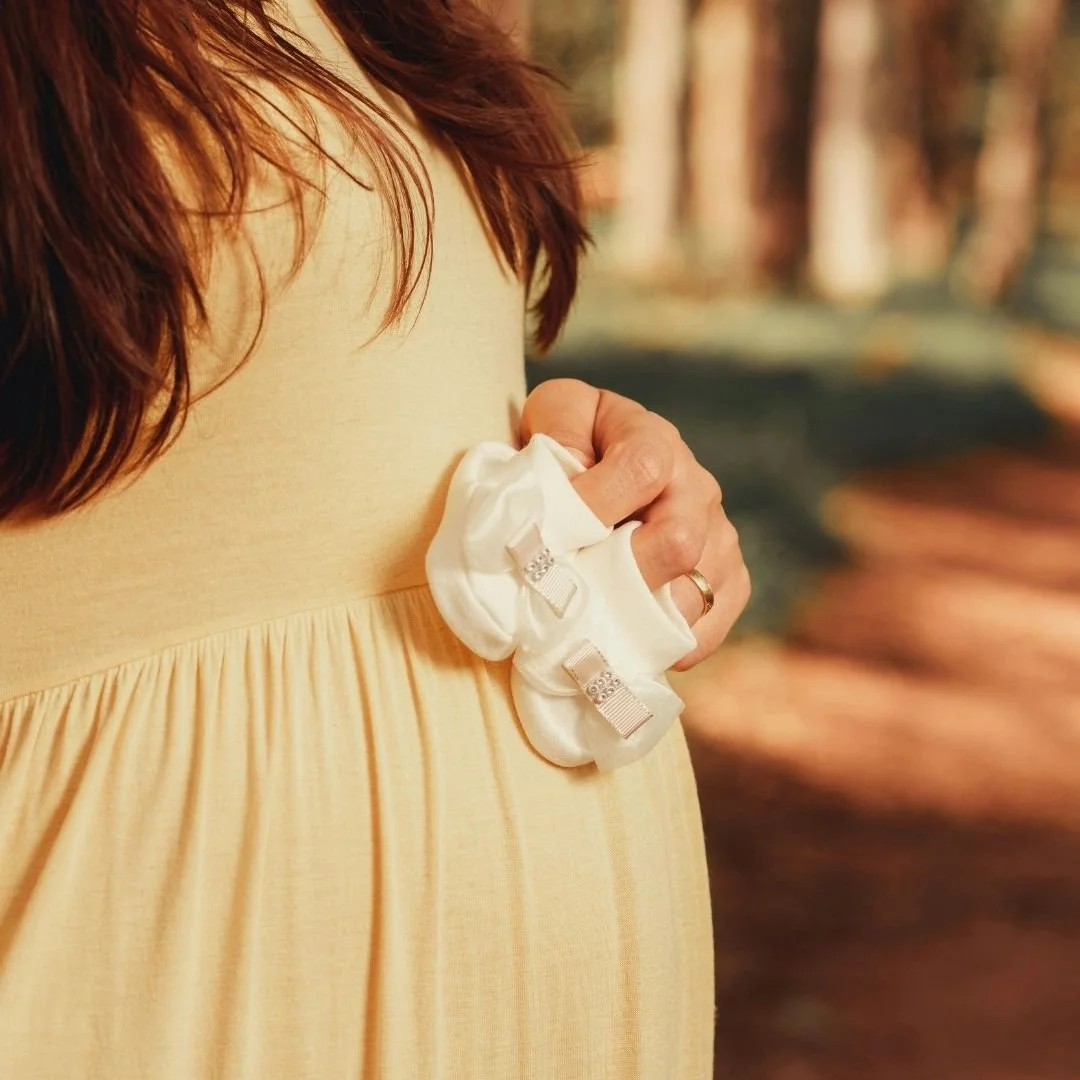 pregnant woman holding baby shoes