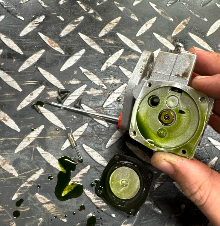 Disassembled carburetor with gasket and old gas. Carburetor cleaning.