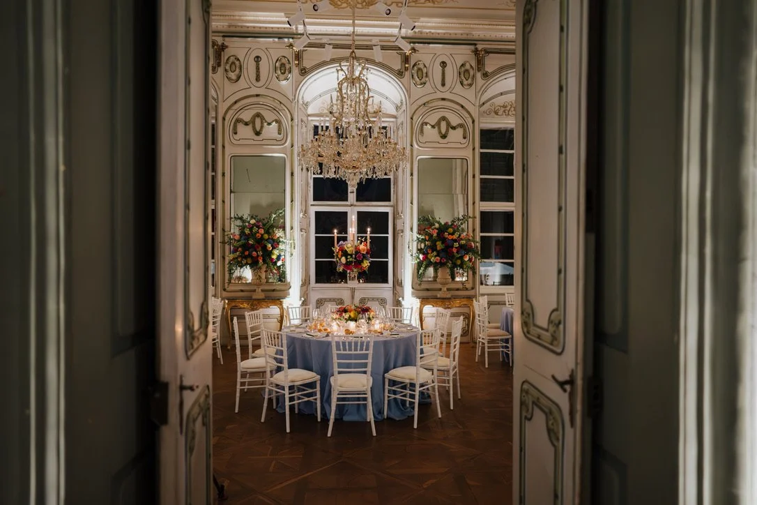 Eleganter festlich gedeckter Raum mit runder Tafel, Blumenarrangements und Kronleuchter in einem historischen Saal vom Schloss Rosegg, es ist eine Hochzeitstafel
