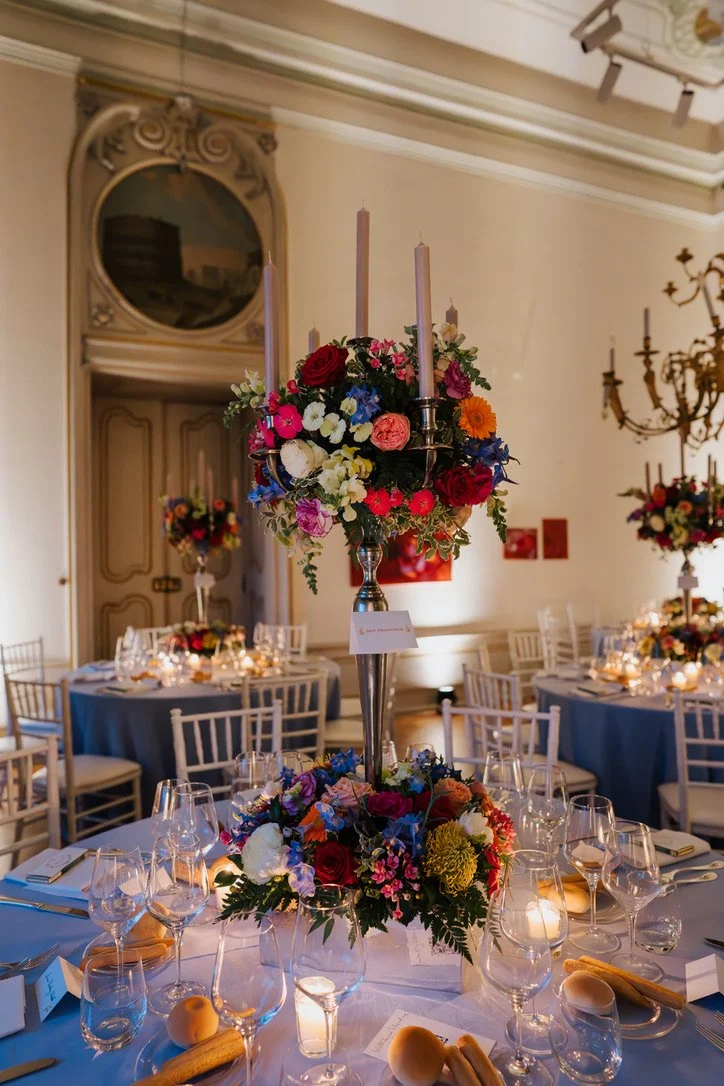 Ein festlich gedeckter Tisch mit Blumenstrauß und Kerzen im festlichen Raum.