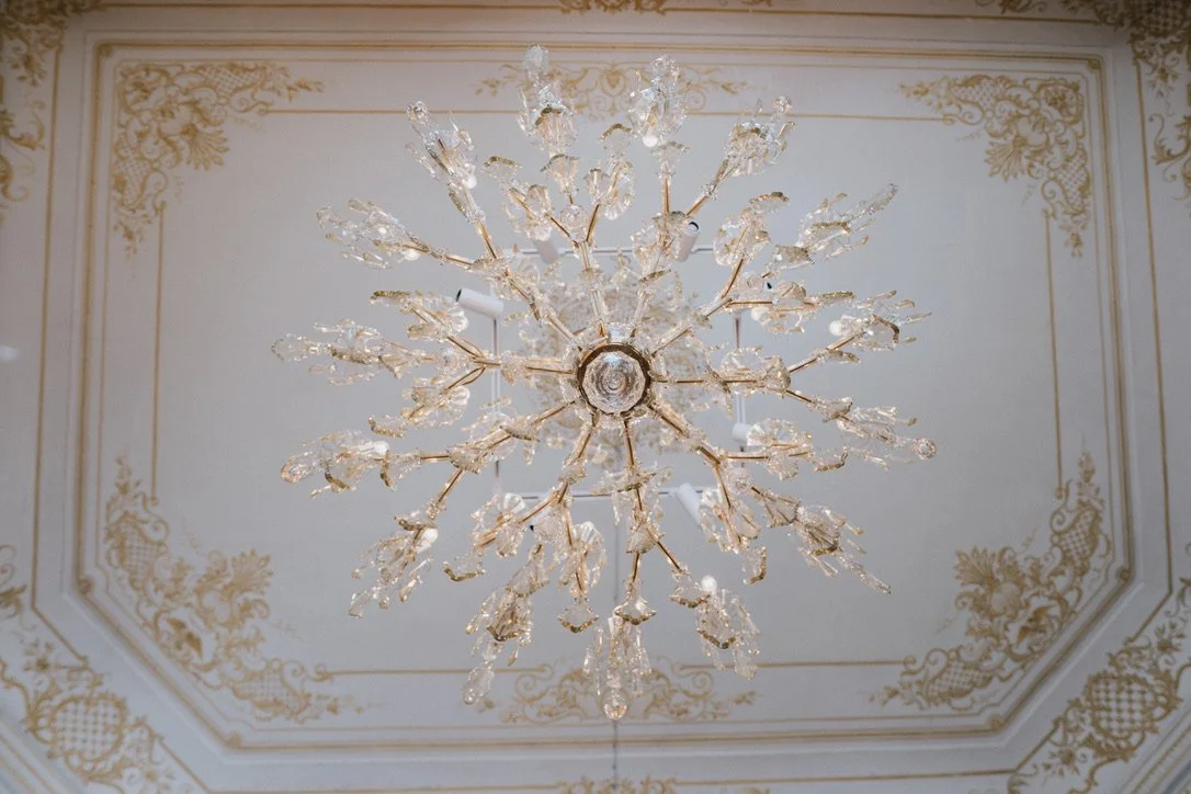 Eleganter Kronleuchter im Schloss Rosegg an einer dekorativen Decke.