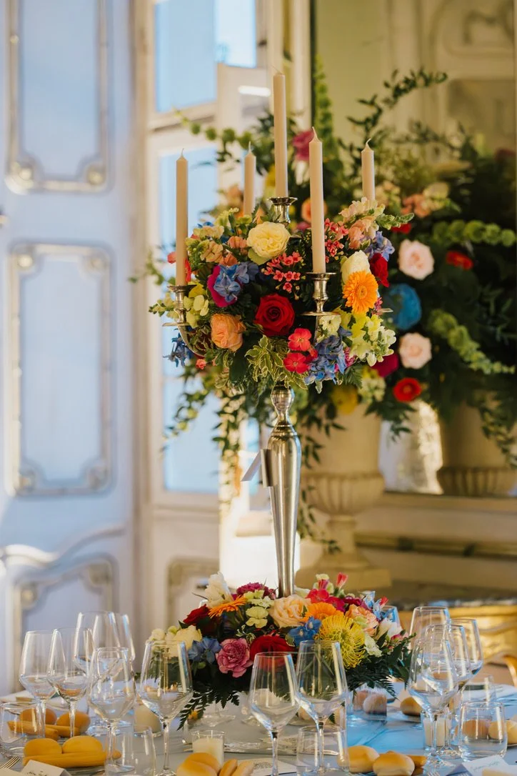 Blumengesteck mit Kerzen auf einem eleganten Tisch bei einer festlichen Veranstaltung, wie einer Hochzeit.