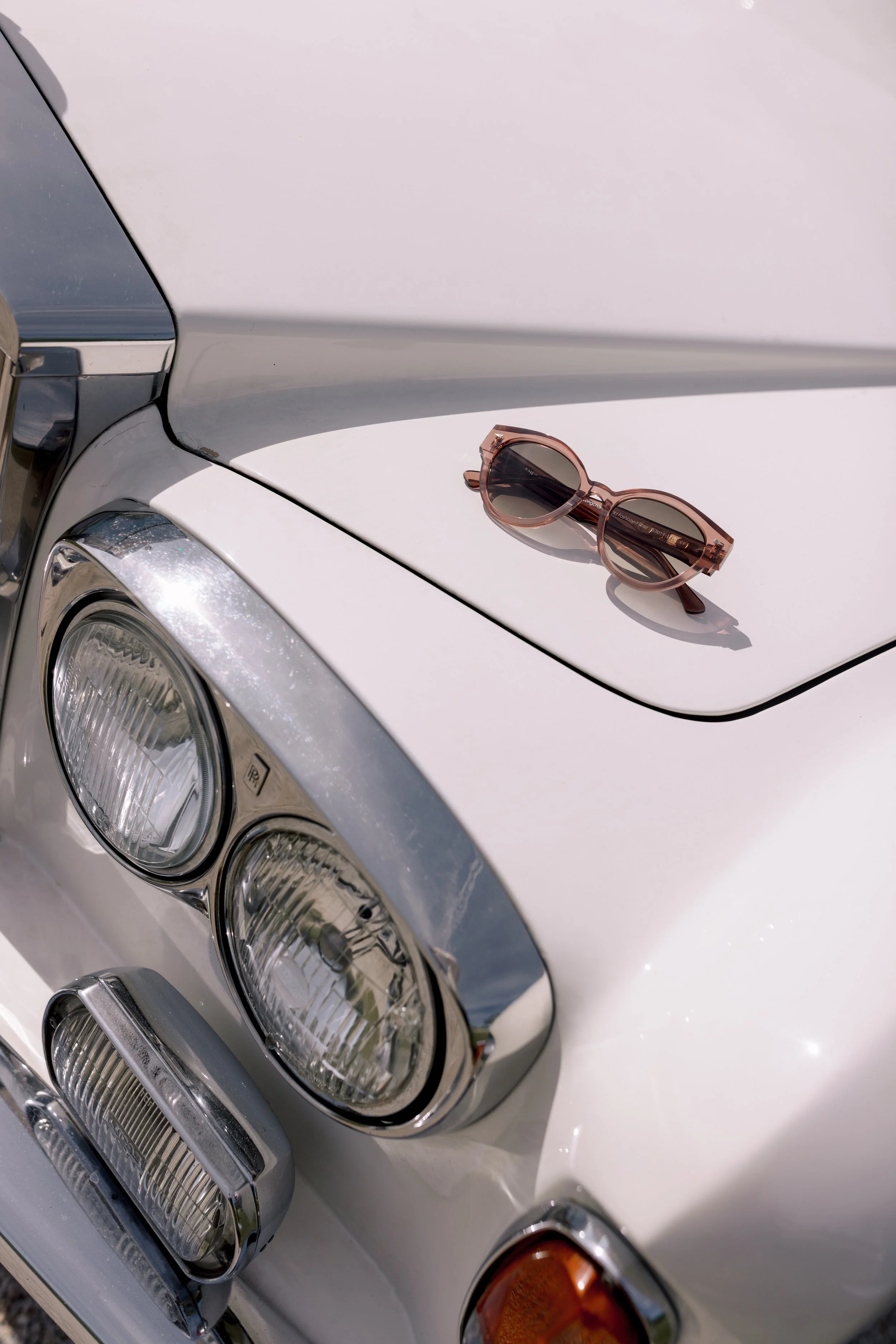 Nahaufnahme des vorderen Teils eines weißen Autos mit einer Sonnenbrille auf der Motorhaube. Ein Hochzeitsauto, Bentley