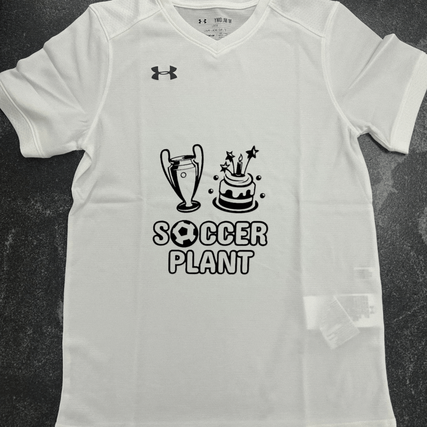 White soccer-themed T-shirt with a trophy, birthday cake with candles, and the words "Soccer Plant" with a soccer ball inside the letter "O".