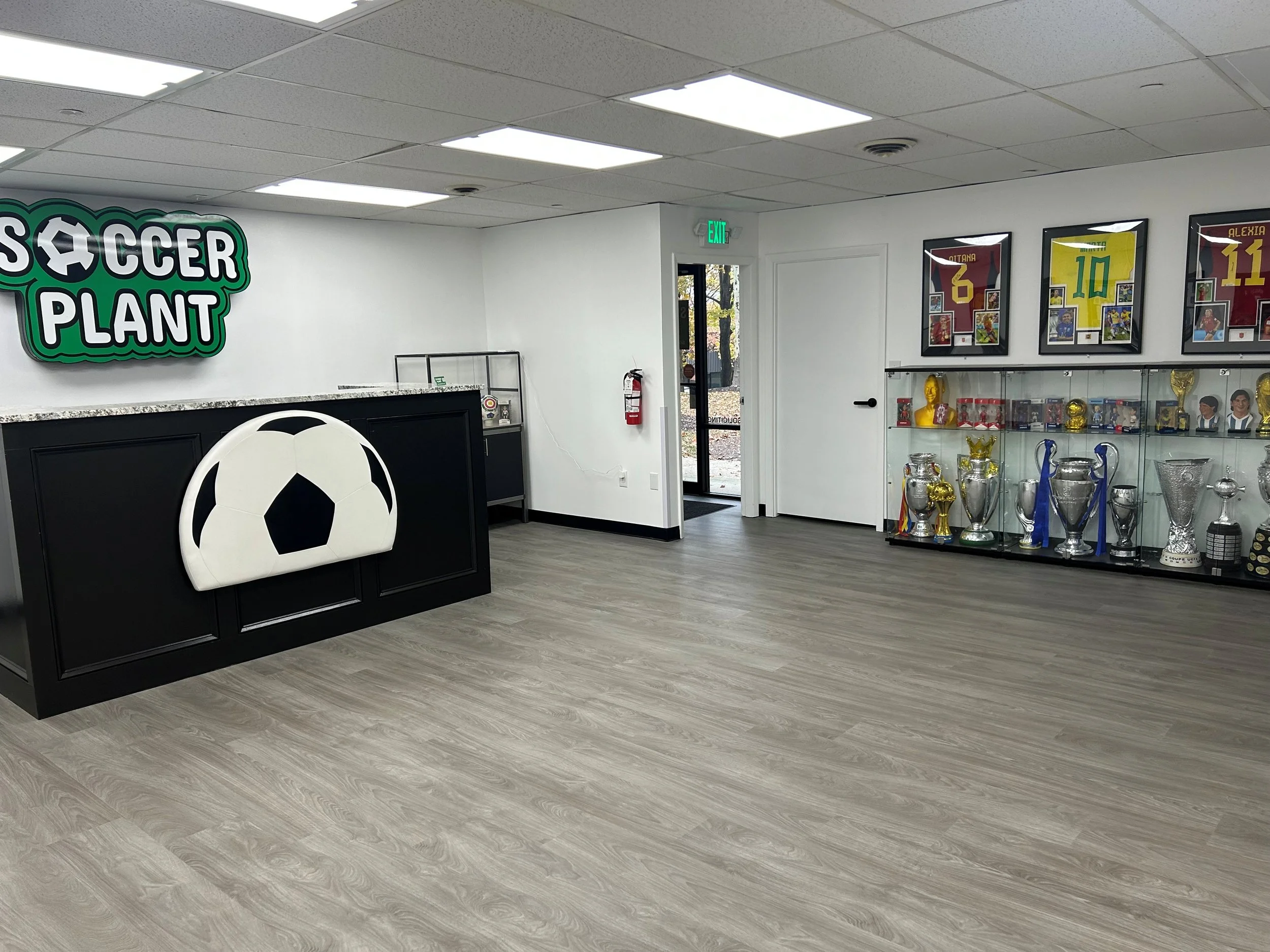 Interior of a soccer training facility with trophies and framed jerseys on the walls.