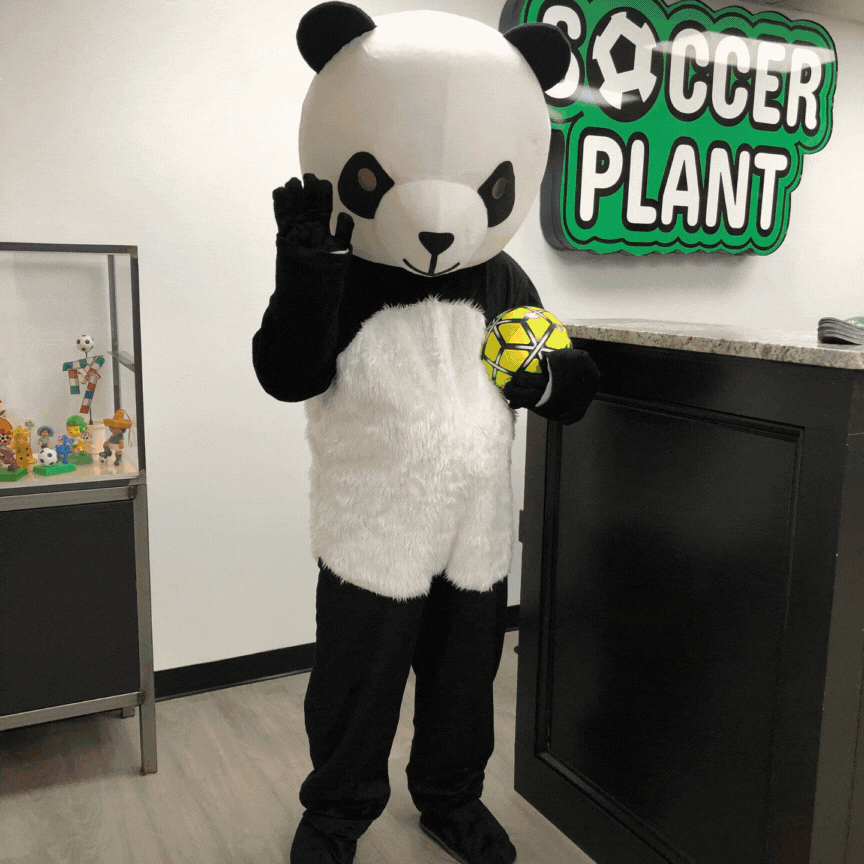 Person in a panda costume holding a yellow and black soccer ball, standing near a sign that reads 'Soccer Plant'.