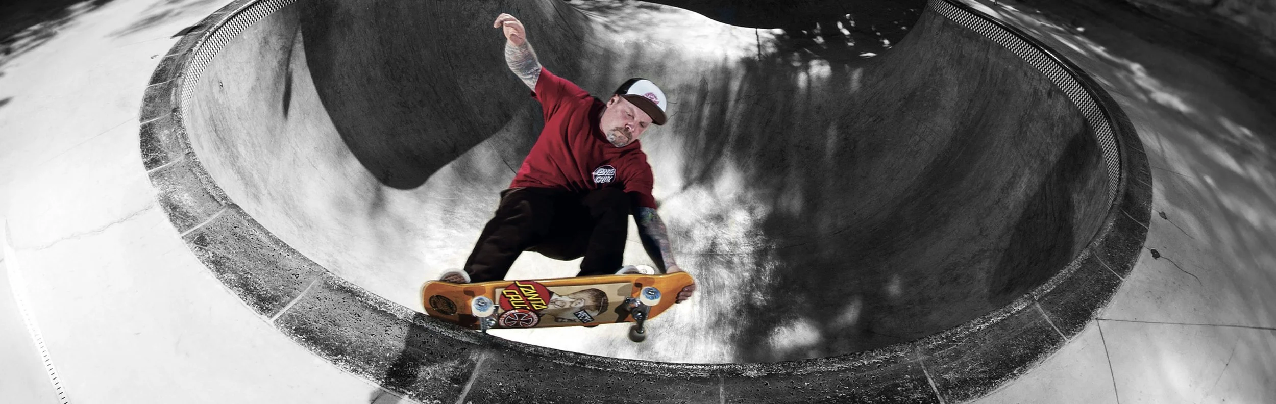 Skateboarder performing a trick inside a concrete skatepark bowl.