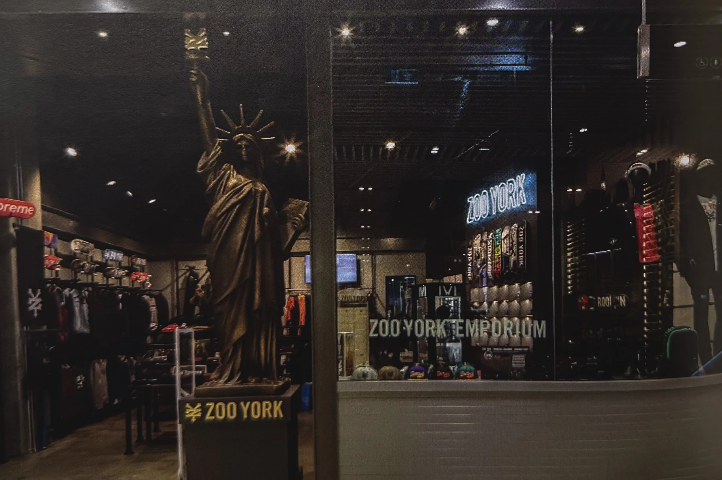 Store display window with a gold statue of the Statue of Liberty and a sign that says 'Zoo York'.