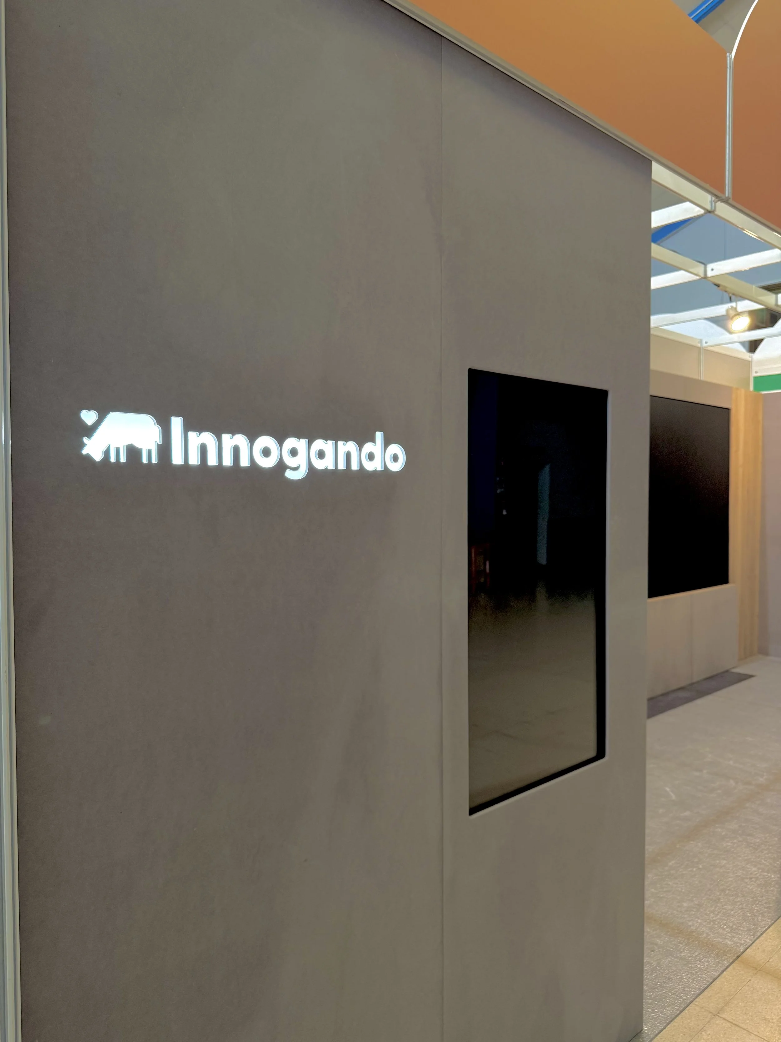 Pantalla con el logotipo y el nombre 'Innogando' en un entorno interior, con paredes de color gris y un pasillo.