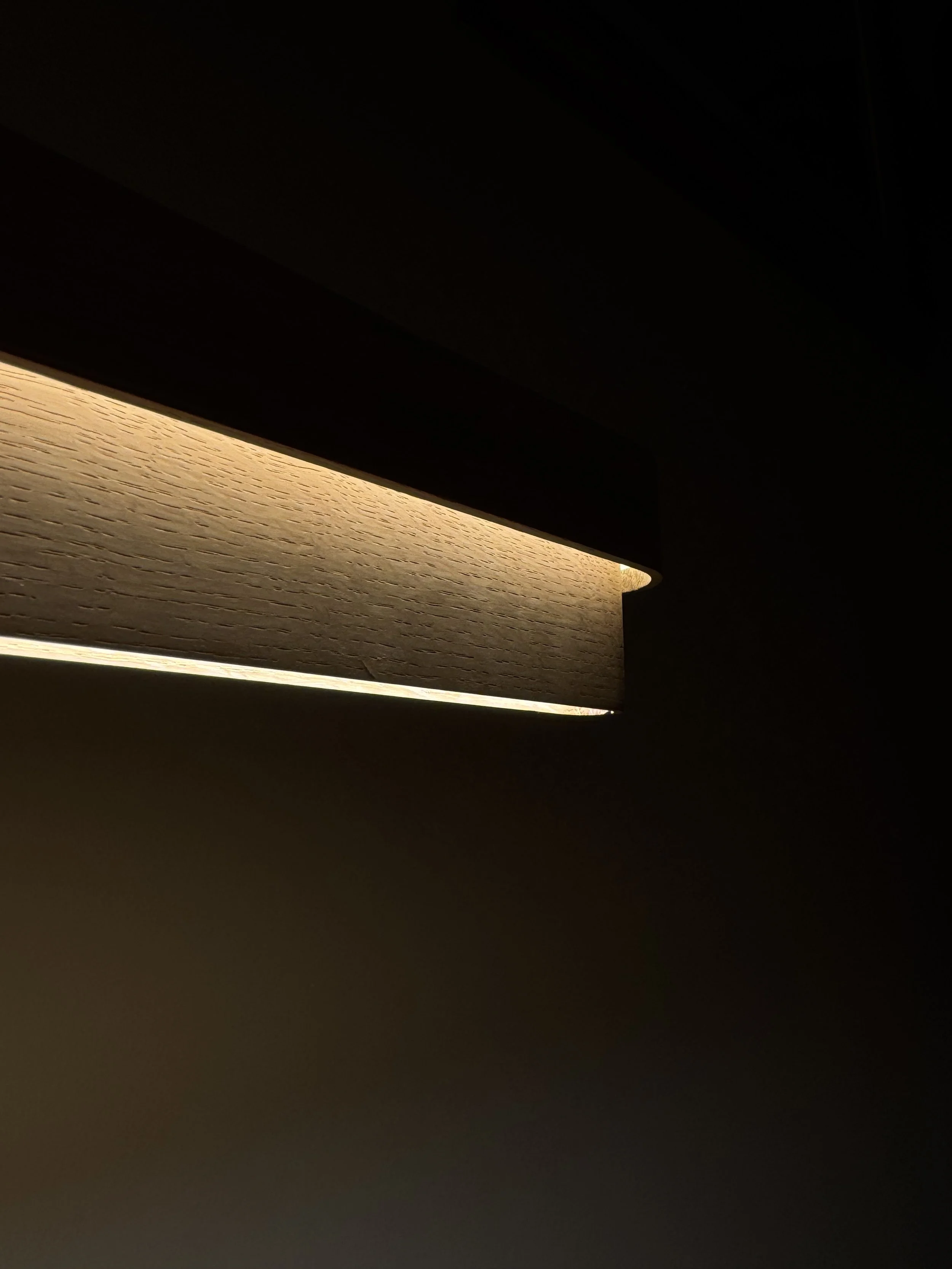 Vista parcial de una lámpara con luz cálida en un entorno oscuro.