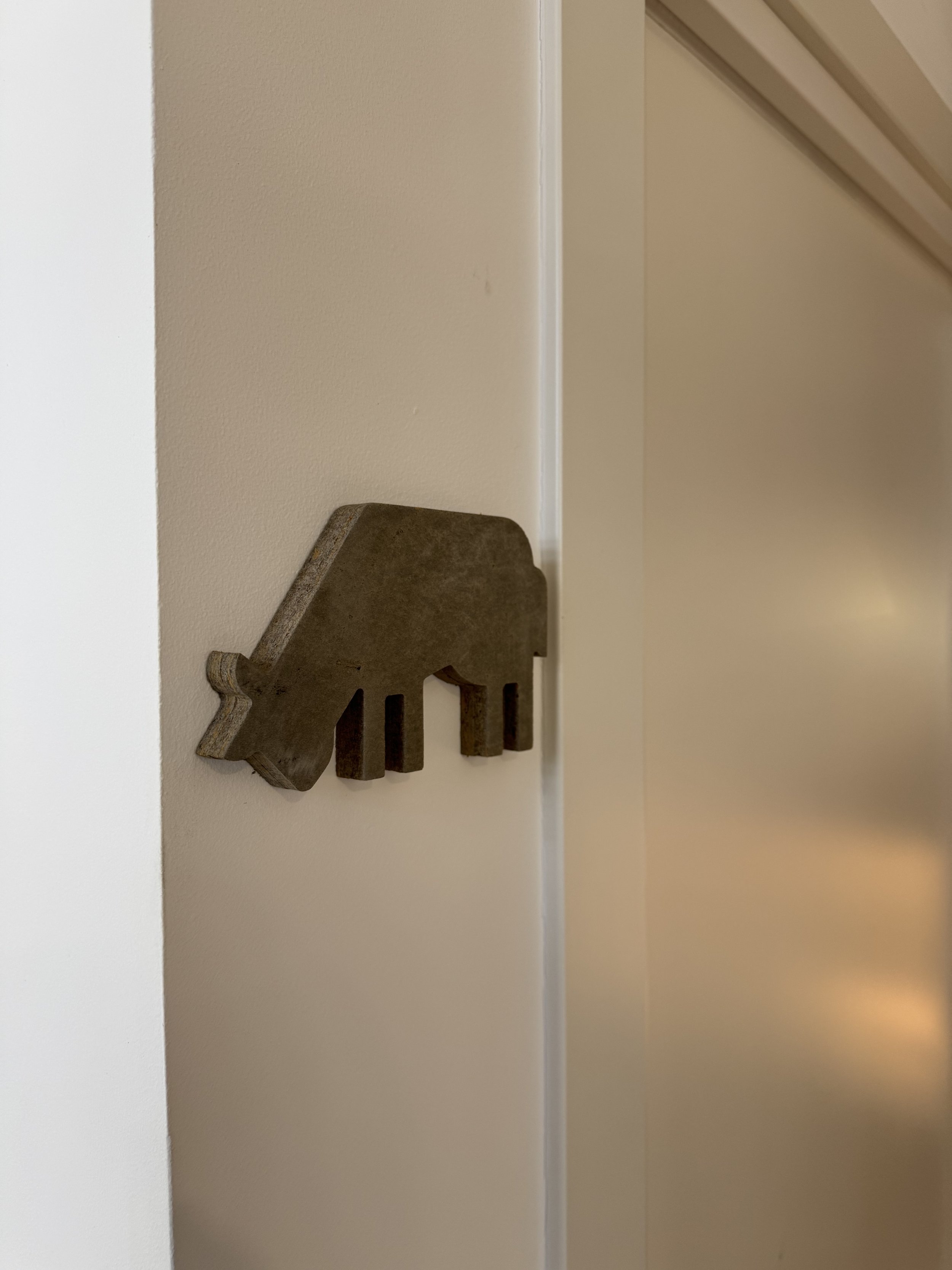 Estatua de madera de un caballo en un estante de una pared blanca.
