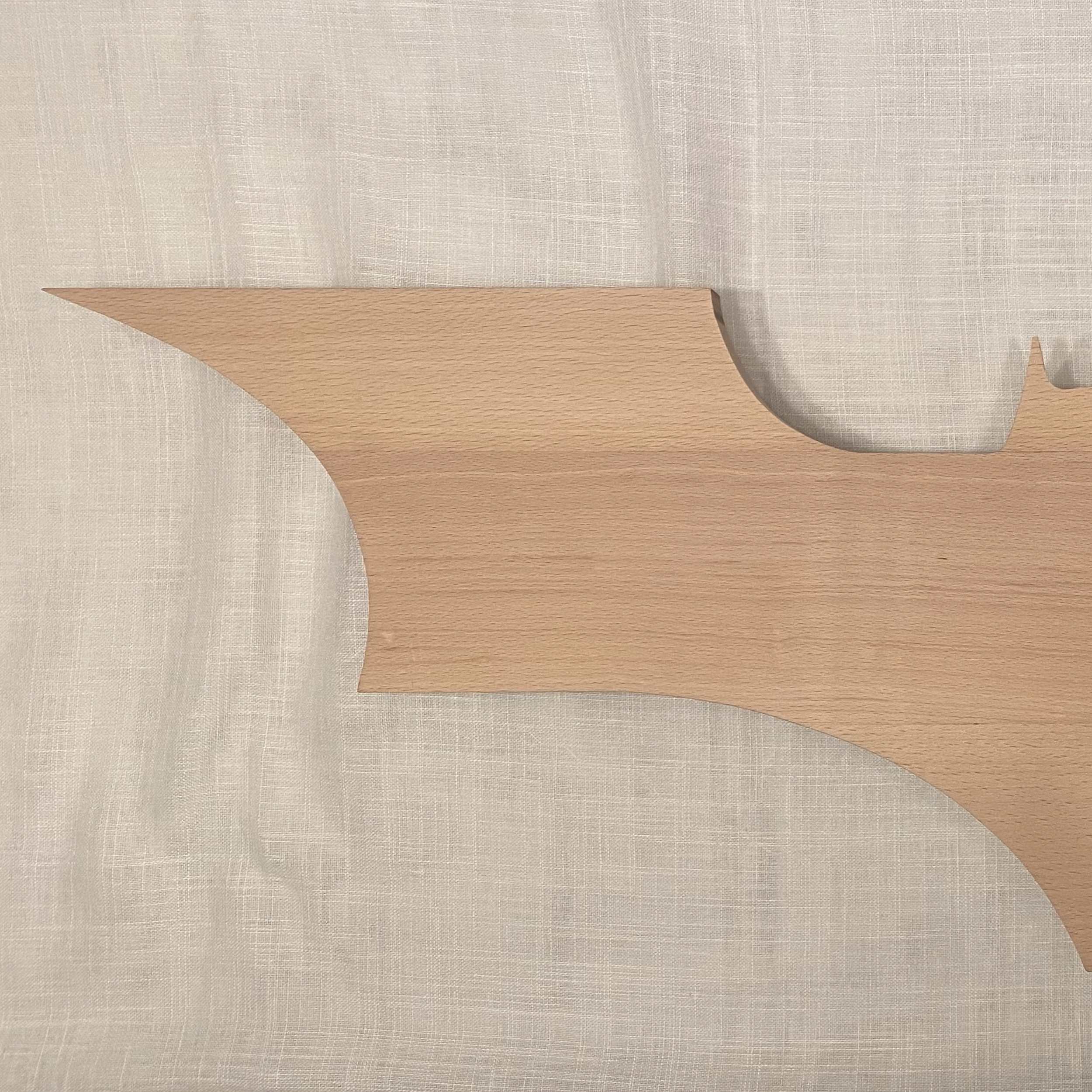 Vista parcial de una figura de madera, colocada sobre tela beige.