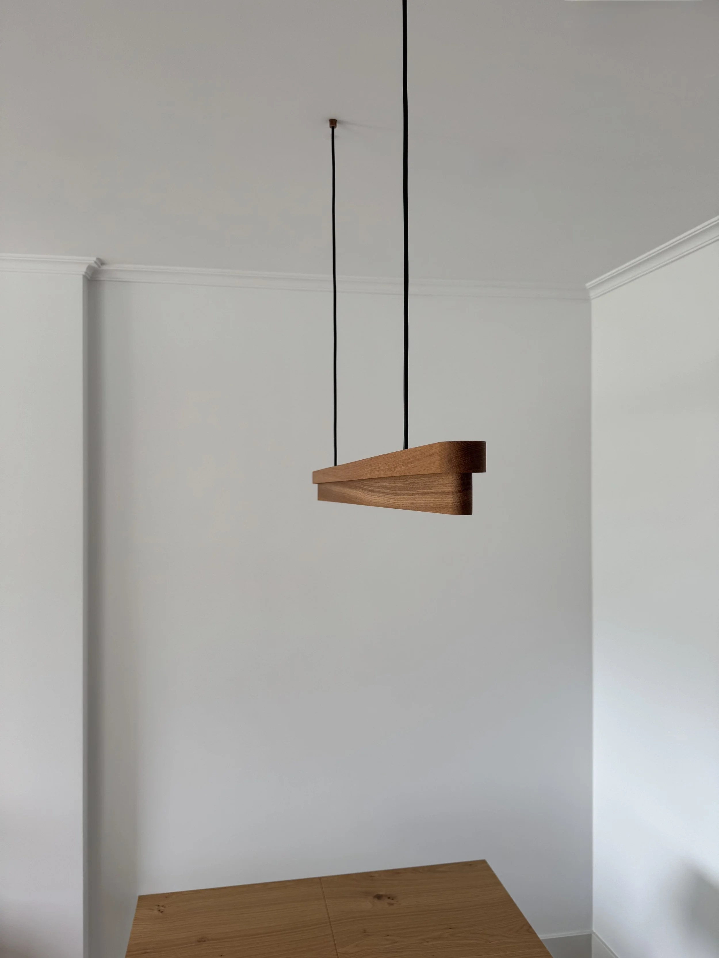 Lámpara colgante moderna de madera suspendida del techo en una habitación blanca