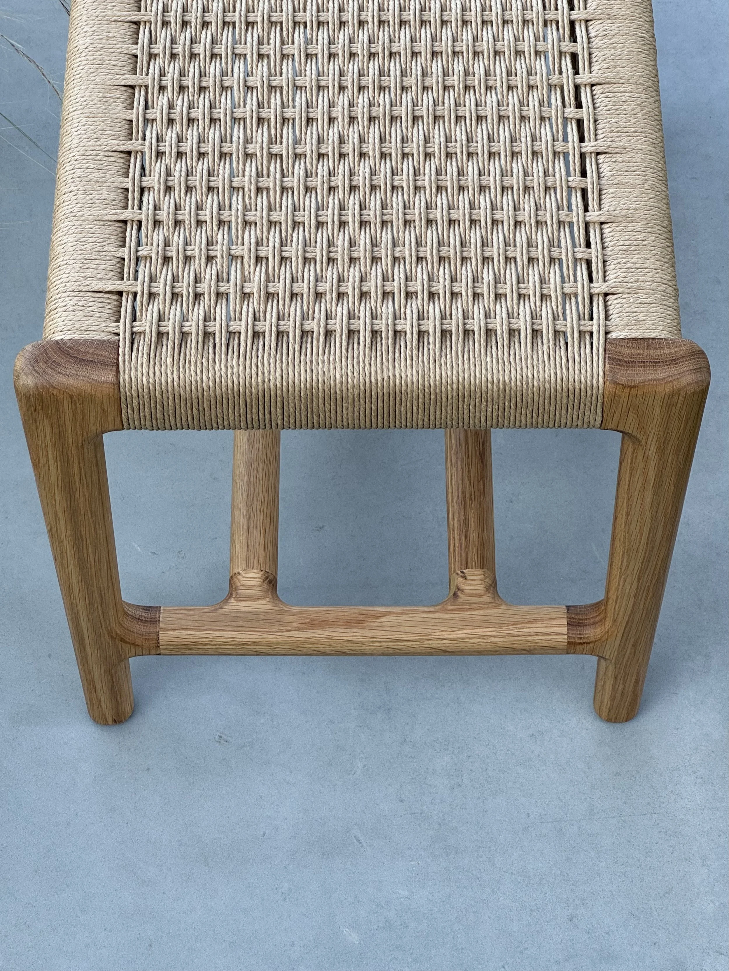 Silla de madera con asiento de cordón entrelazado.
