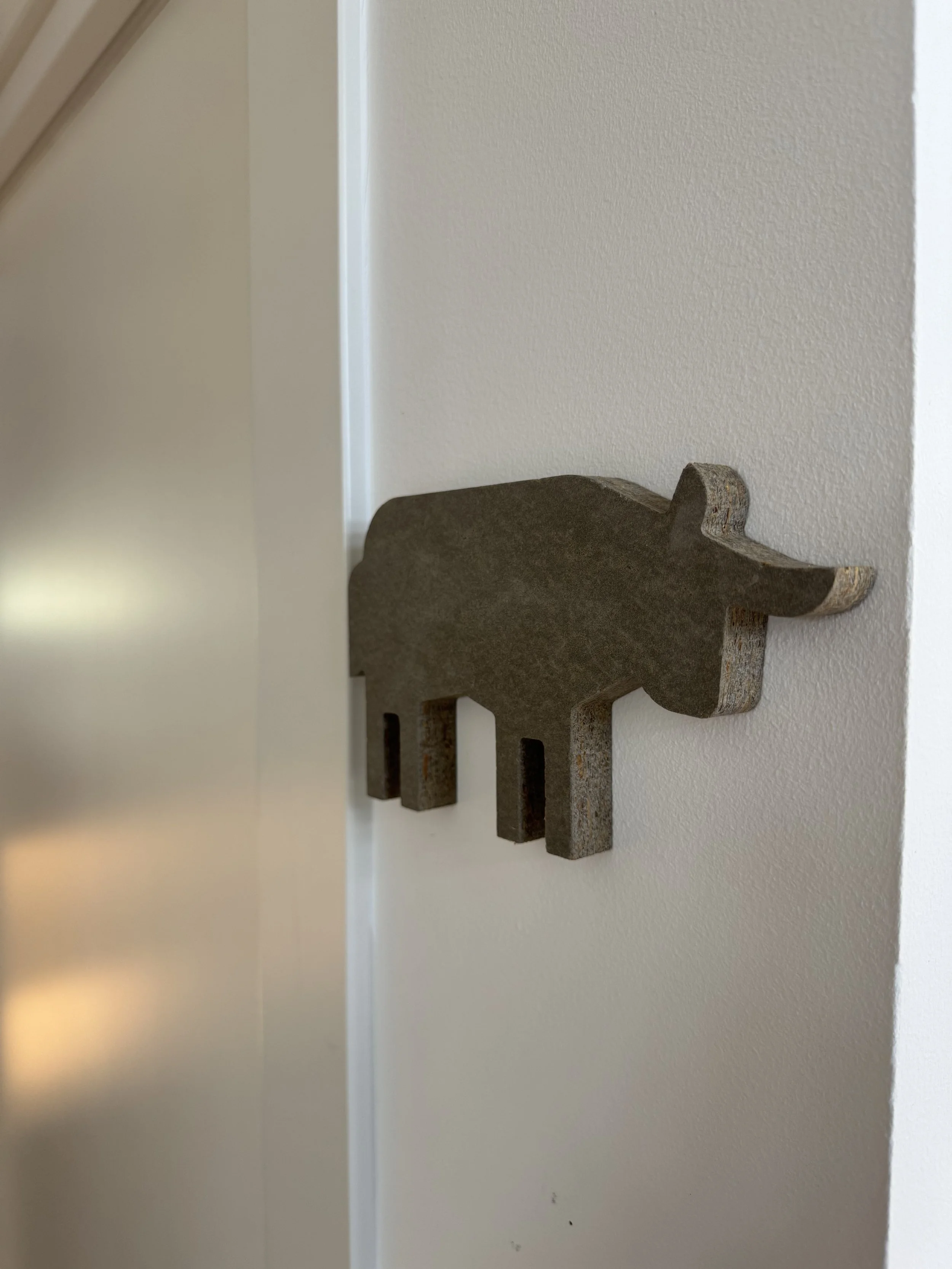 Pieza de madera en forma de llave pegada en la pared con textura lisa y color blanca.