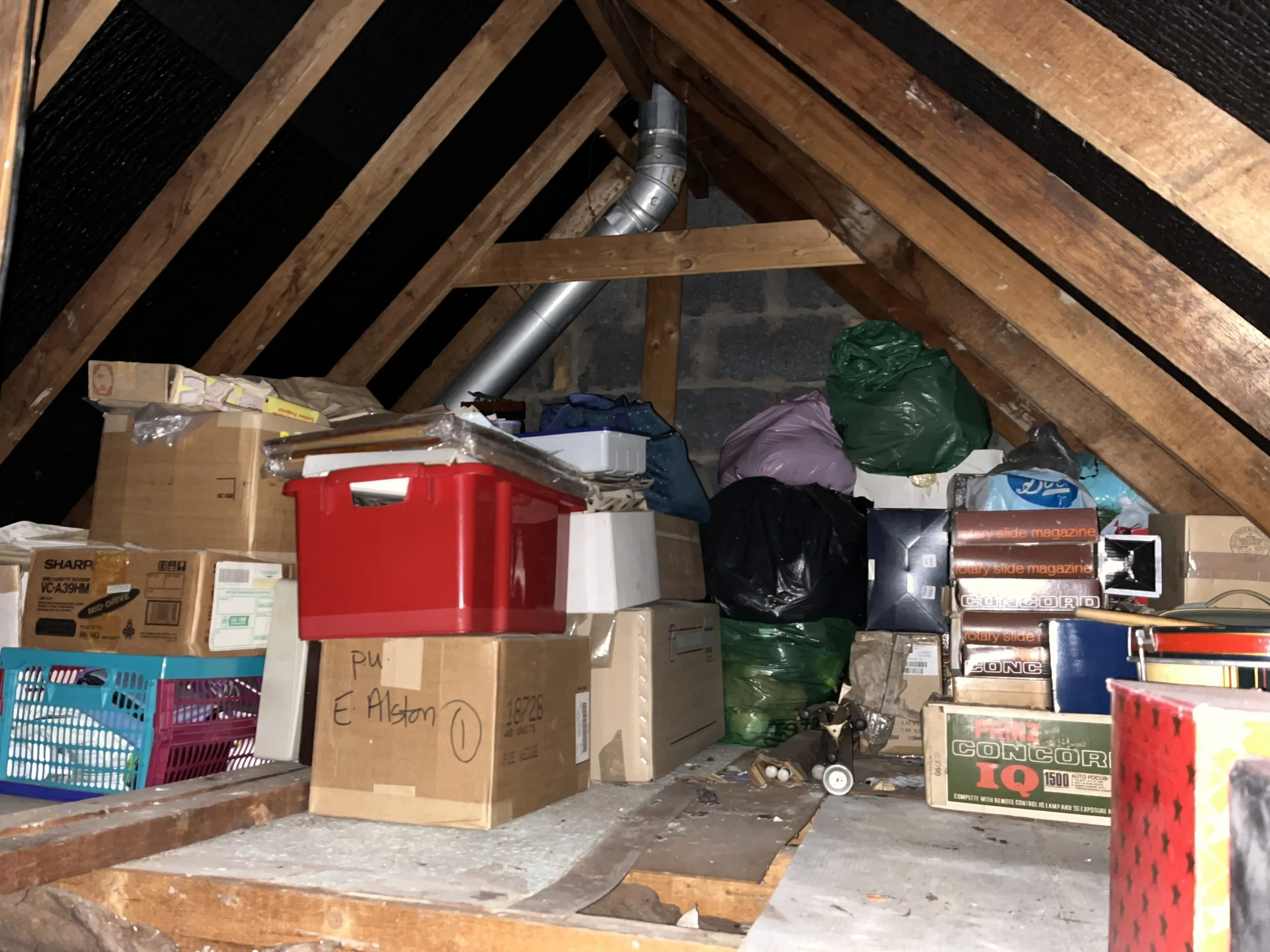 Attic house clearance in Staffordshire and Derbyshire with cluttered loft full of boxes, storage bins, and unwanted household items ready for removal