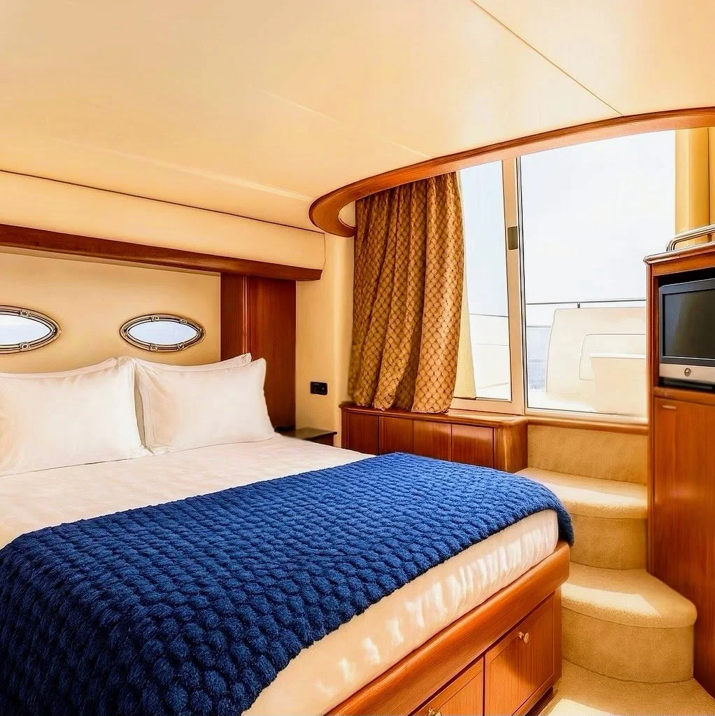Luxurious bedroom with large bed, white bedding, blue throw blanket, wooden furniture, a window with curtains, and a small television.