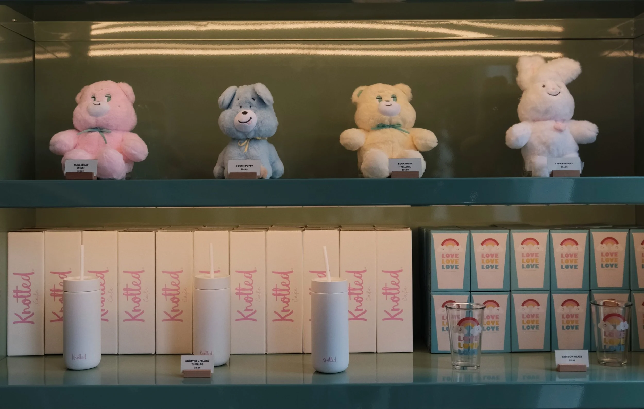 A shelf display with pastel plush toys, tumblers, and boxed merchandise at the Cafe Knotted's LA Arts District location