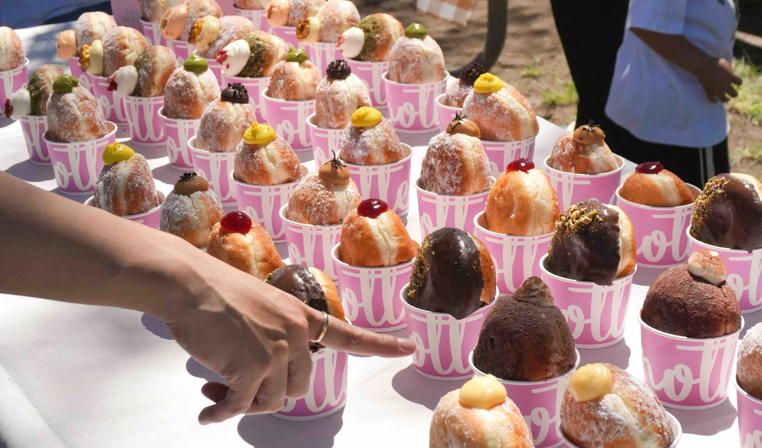 Rows of assorted filled donuts in pink Knotted cups at a catering event