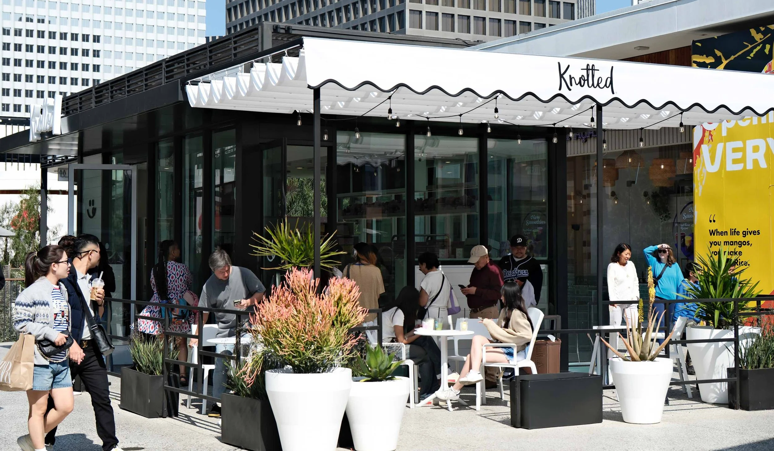 Customers lined up outside the Knotted bakery café, with outdoor seating and branded awning.