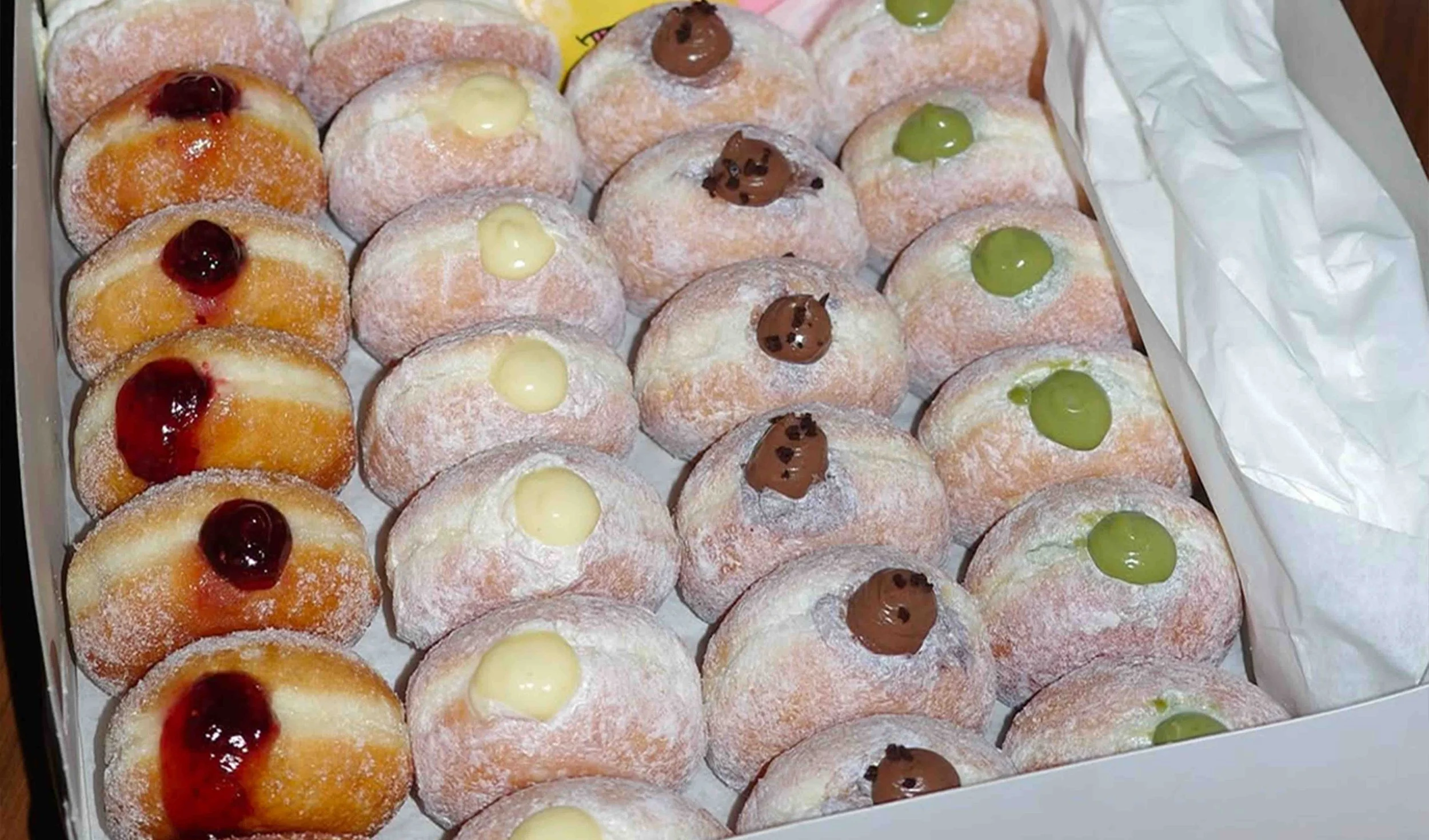 Assorted filled donuts arranged in a catering box