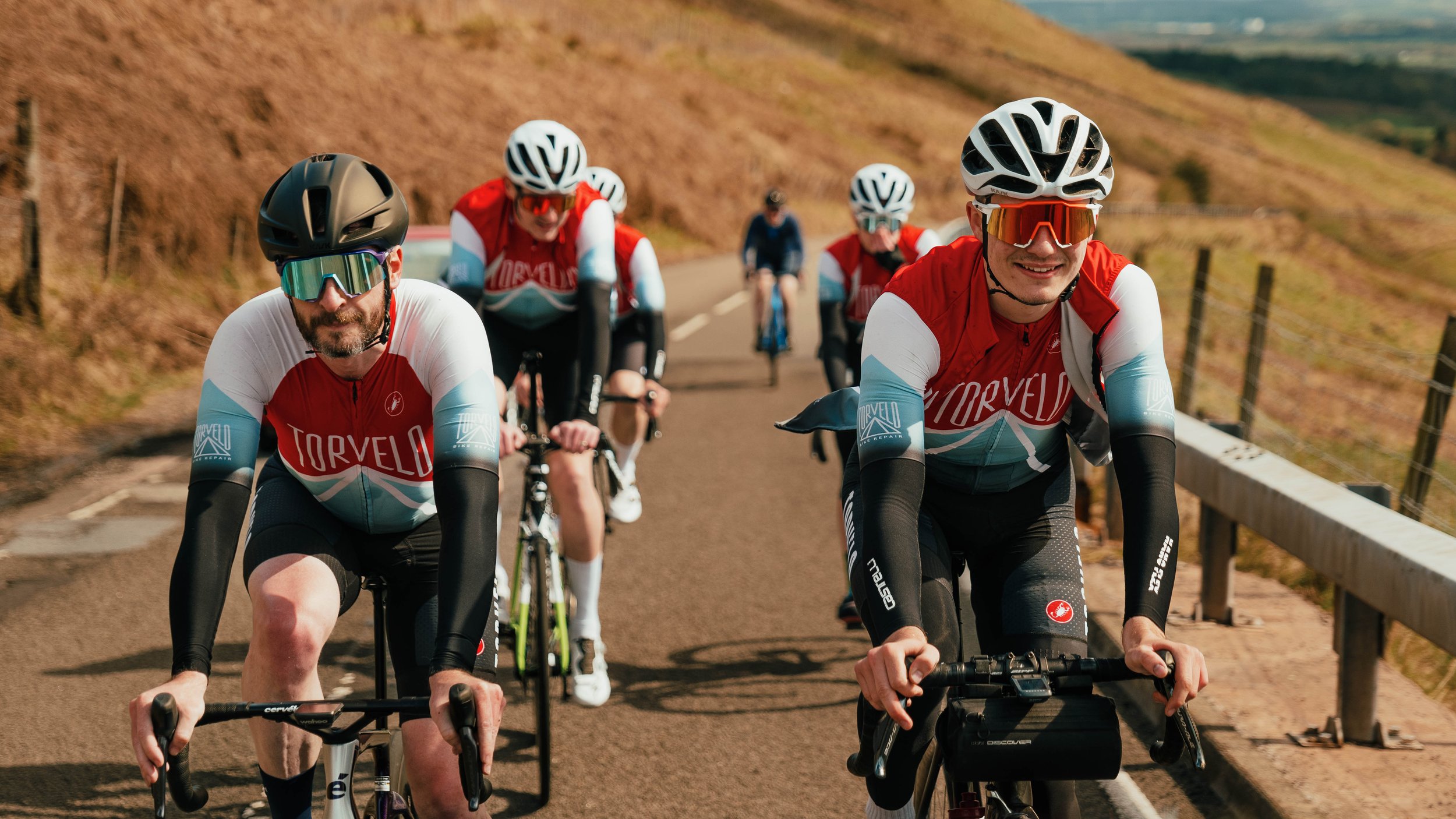 Torvelo Cycling Race Team. Cyclists in red and blue jerseys riding on a road. Sports Photography