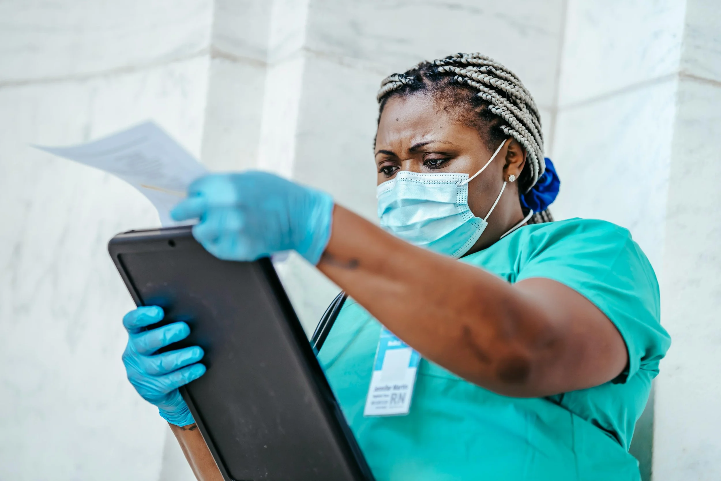 Nurse in surgical scrubs reviewing documents on a tablet, illustrating the psychological services and evaluations for pre-surgical evaluations and more at MindView Psychology