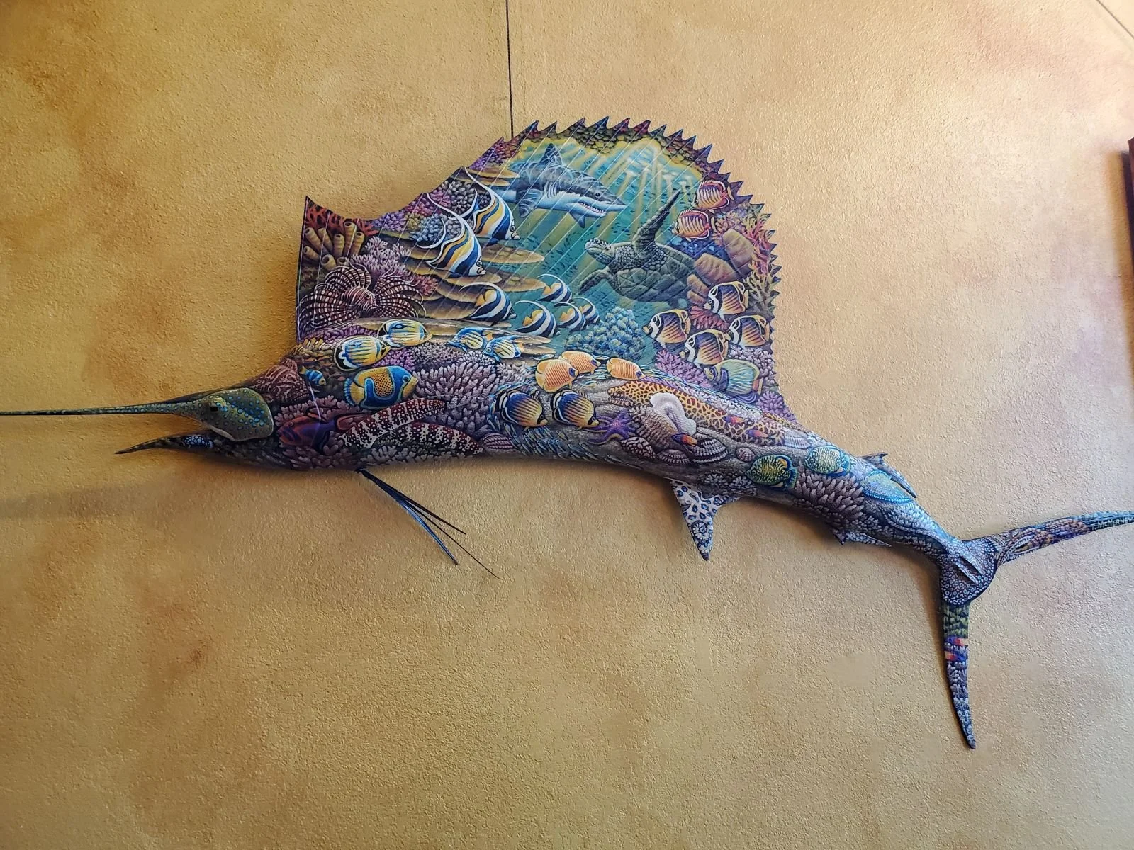 Swordfish with an underwater reef scene and tropical fish painted on it.