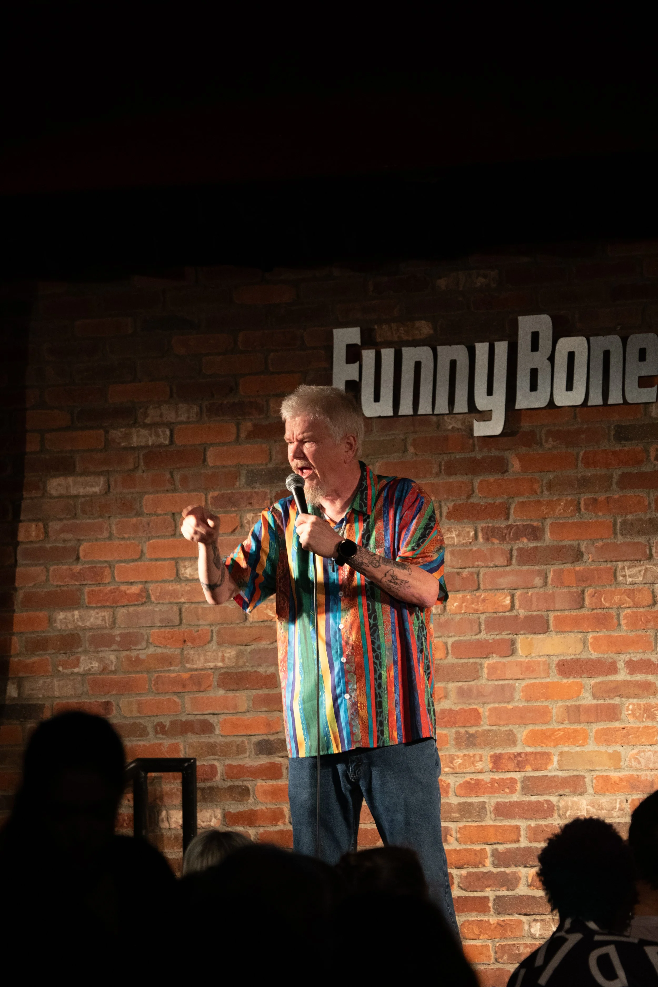 Comedy Photography by Will Locke in Norfolk, VA. Comedian points at crowd while telling jokes. Crowd is in screen. 