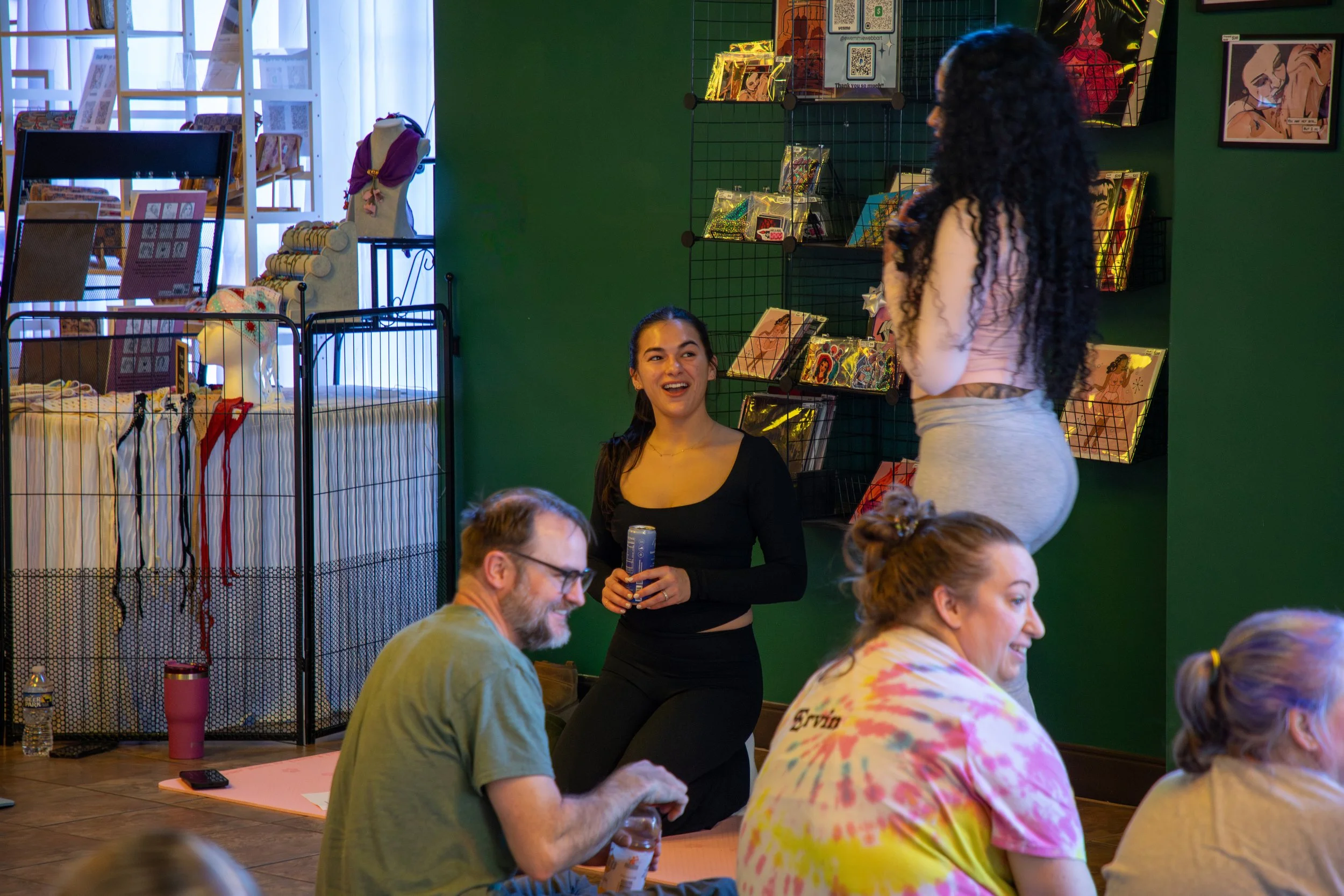 Marketing and Event Photography by Will Locke. People sitting on the floor and chatting in a cozy indoor space with art and books on display on the walls and shelves.