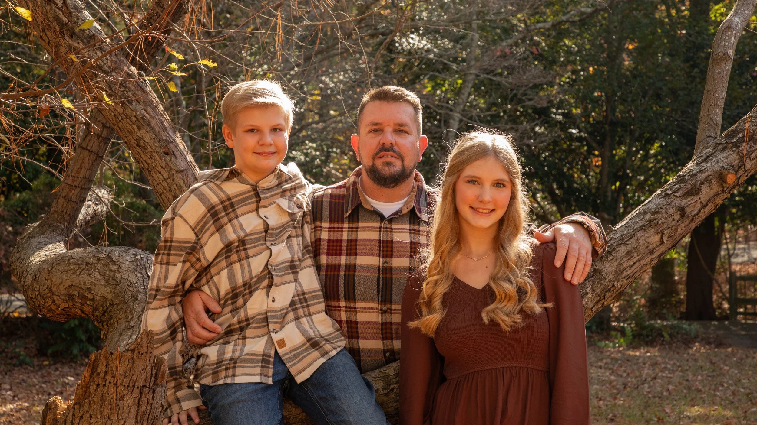 Photo & Video by Will Locke Family Photography at the Mariners’ Museum and Park in Newport News, Virginia. A man with a beard standing outdoors beside a boy and a girl, all smiling, in a park with trees and autumn foliage.