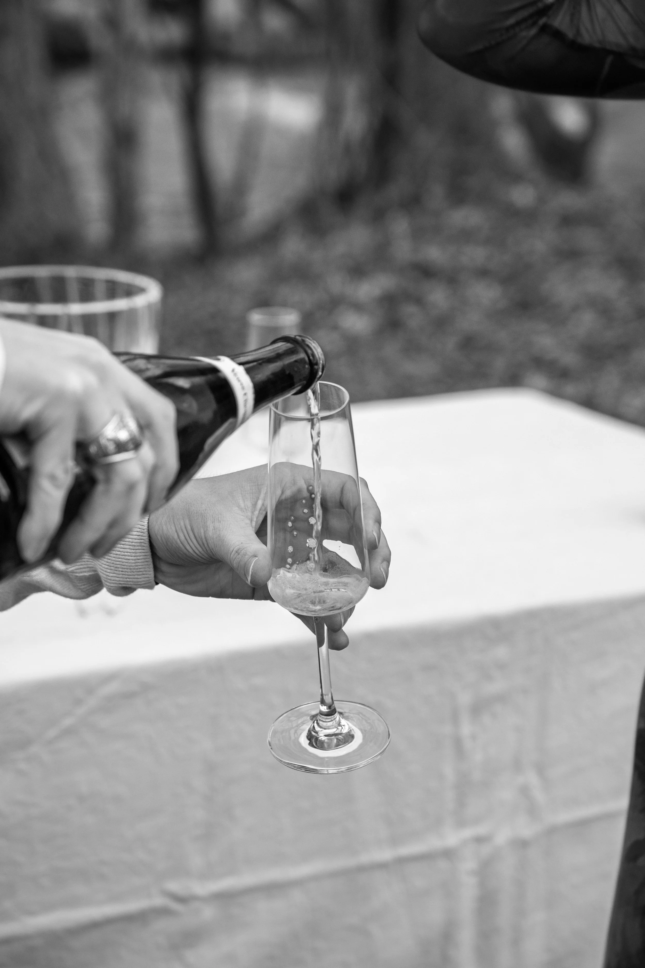 Engagement Photography by Will Locke near Richmond, VA in Montpelier. A glass of champagne is being poured, with a table and a bottle of champagne in the background.