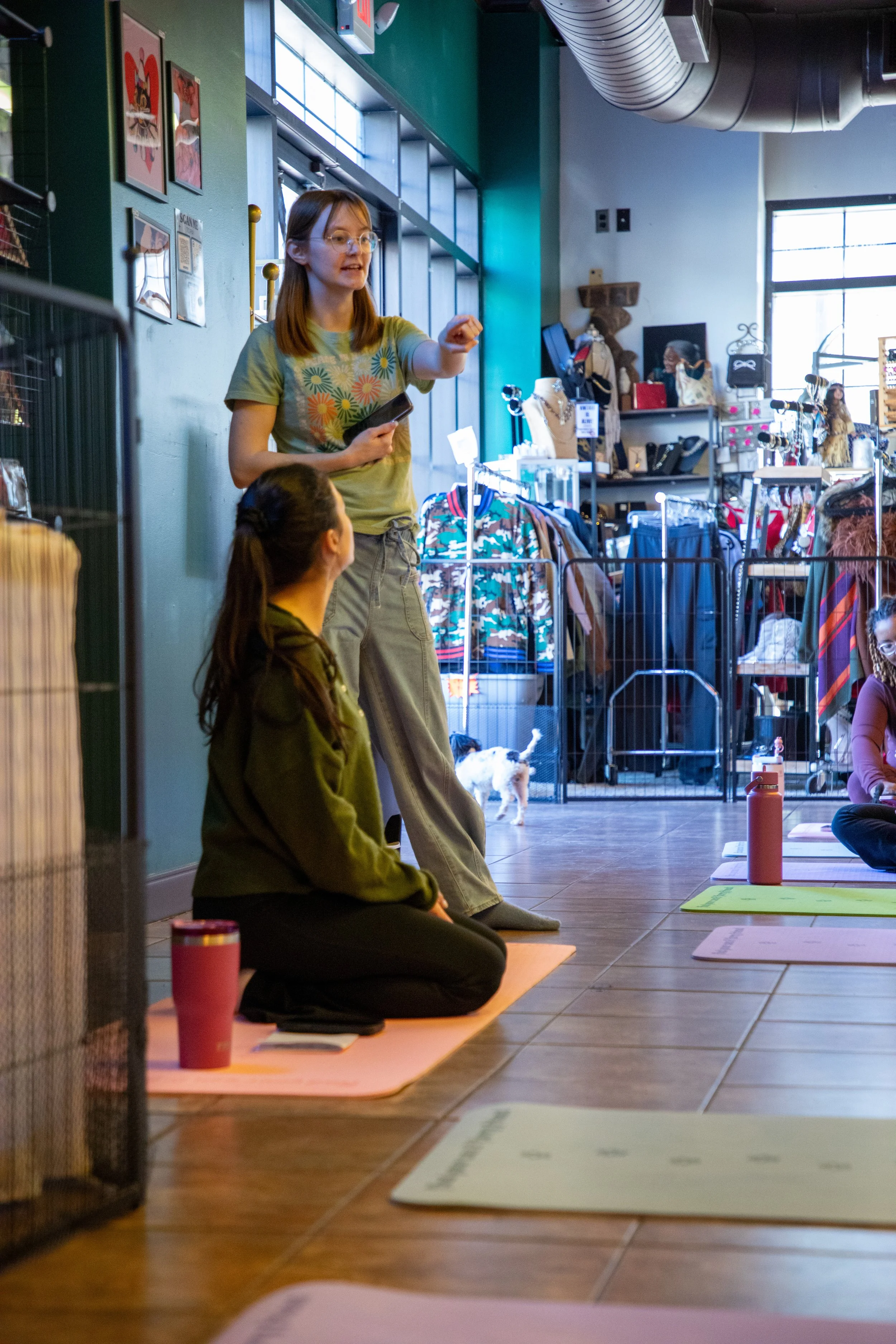 Marketing and Event Photography by Will Locke. A yoga instructor sits on the ground has long dark hair tied back and is sitting on a yoga mat, with a water bottle and papers in front of her. 