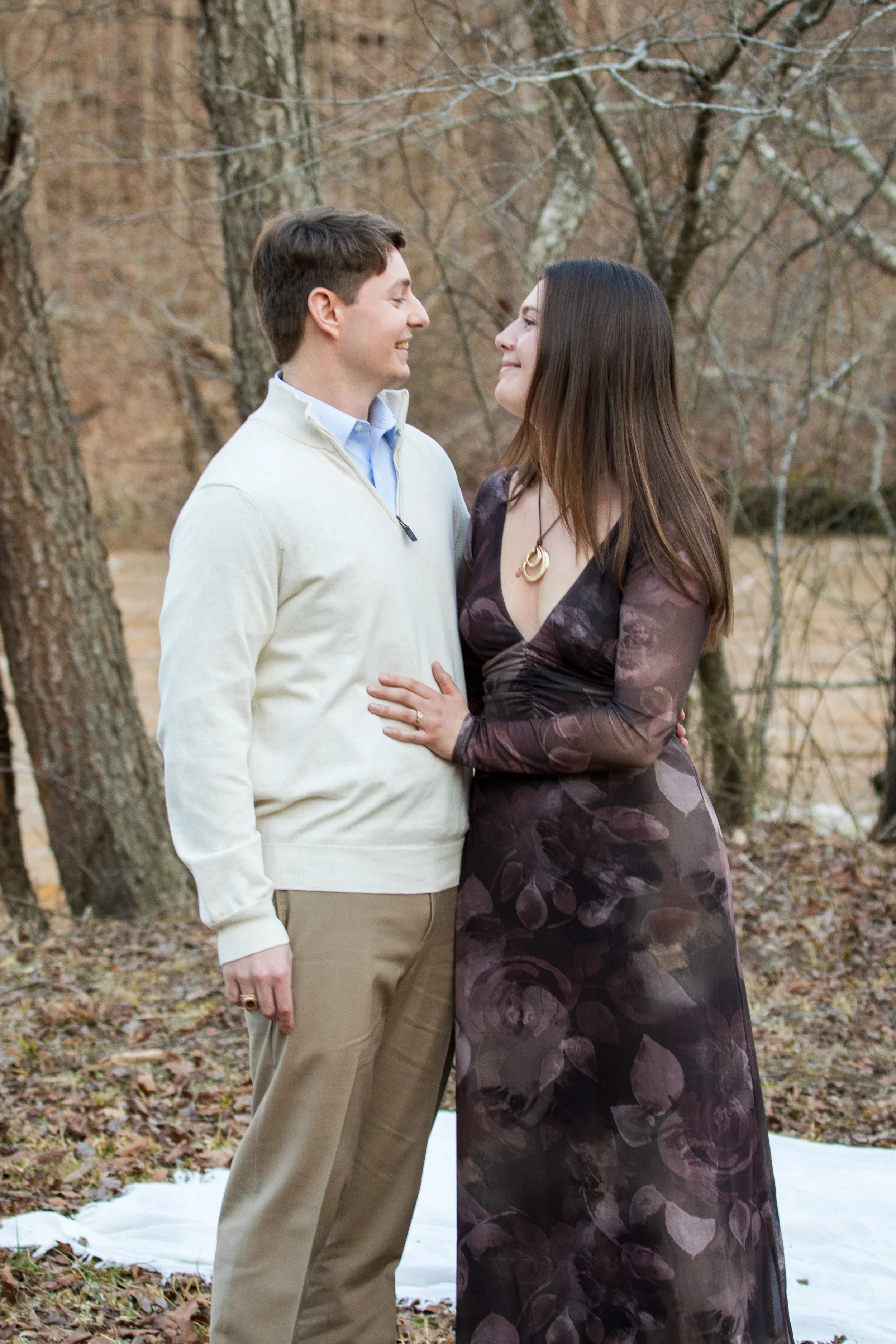 Engagement Photography by Will Locke near Richmond, VA in Montpelier. A man and woman smiling at each other while holding champagne glasses outdoors during sunset, with a table of flowers nearby.