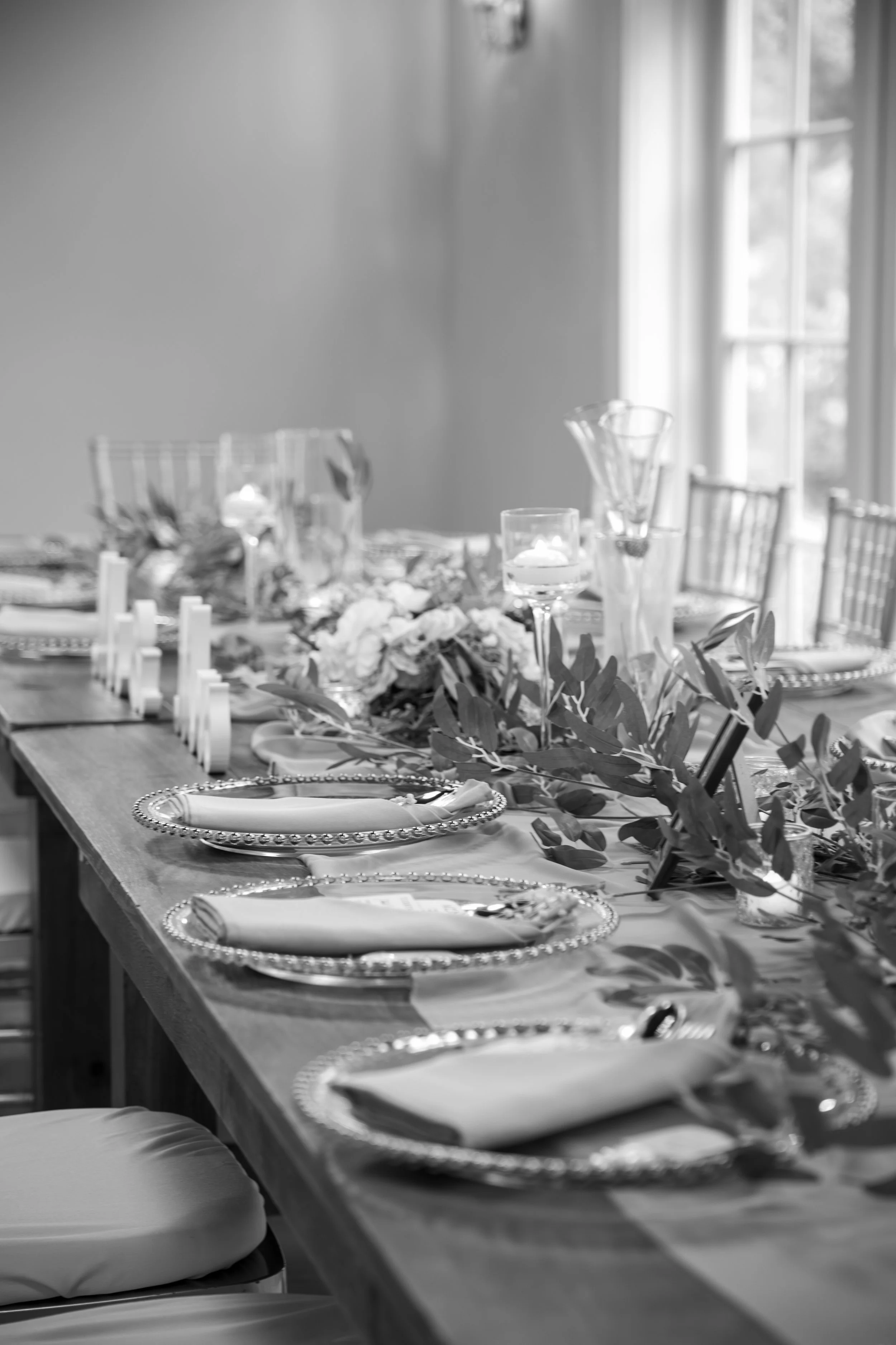 Wedding Photography by Will Locke. Table setting with plates, napkins, silverware, candles, and greenery, ready for a meal.