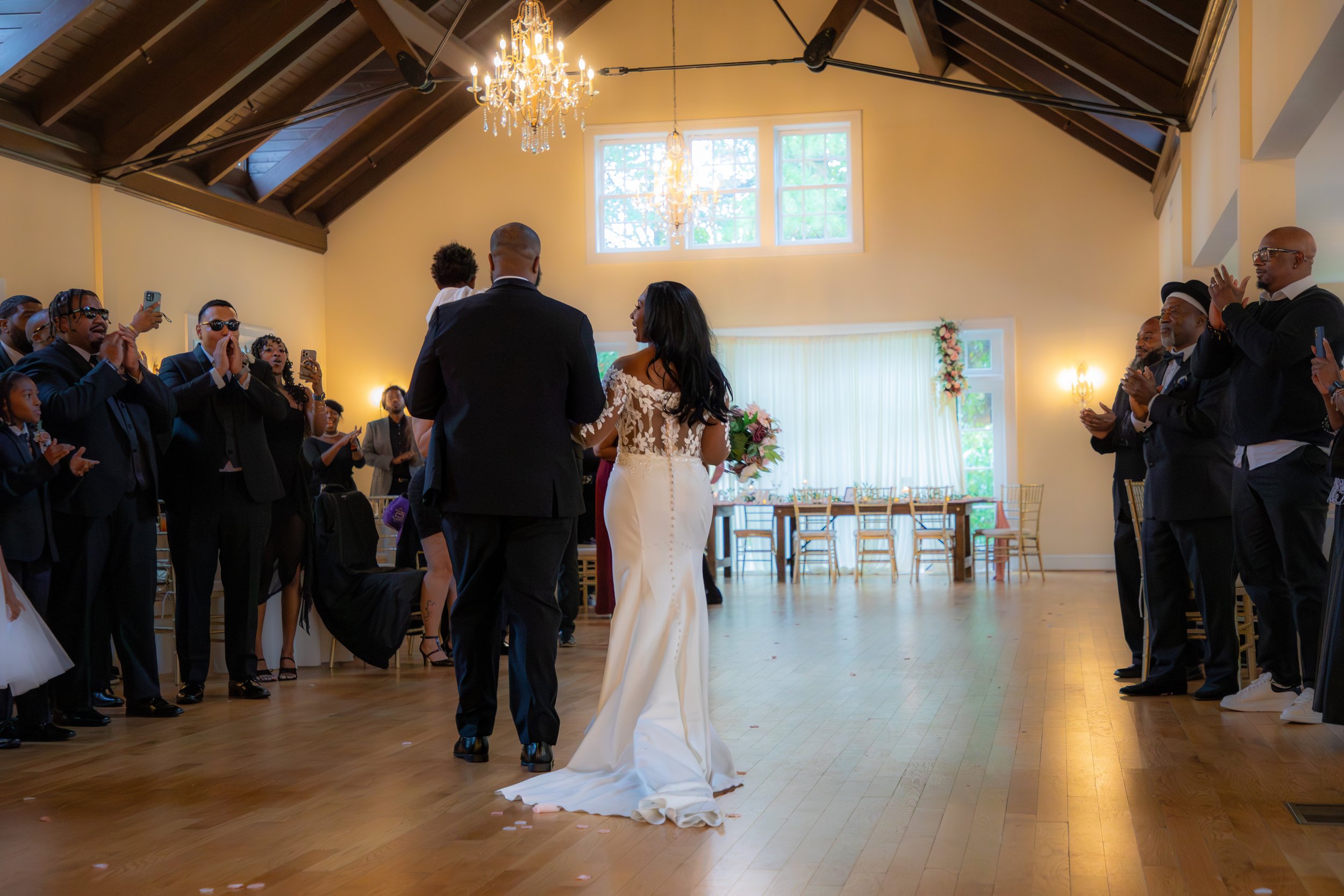 Wedding Photography by Will Locke. Couple dances in the center of a wedding reception hall surrounded by guests clapping and taking photos.